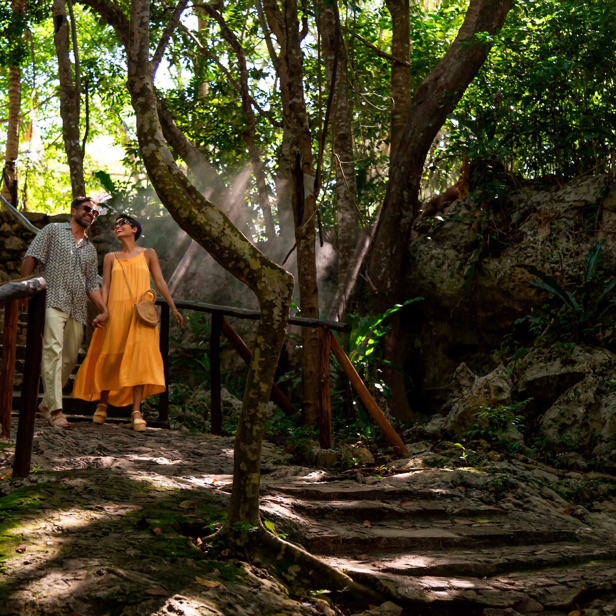 a man and woman standing on a bridge in the woods