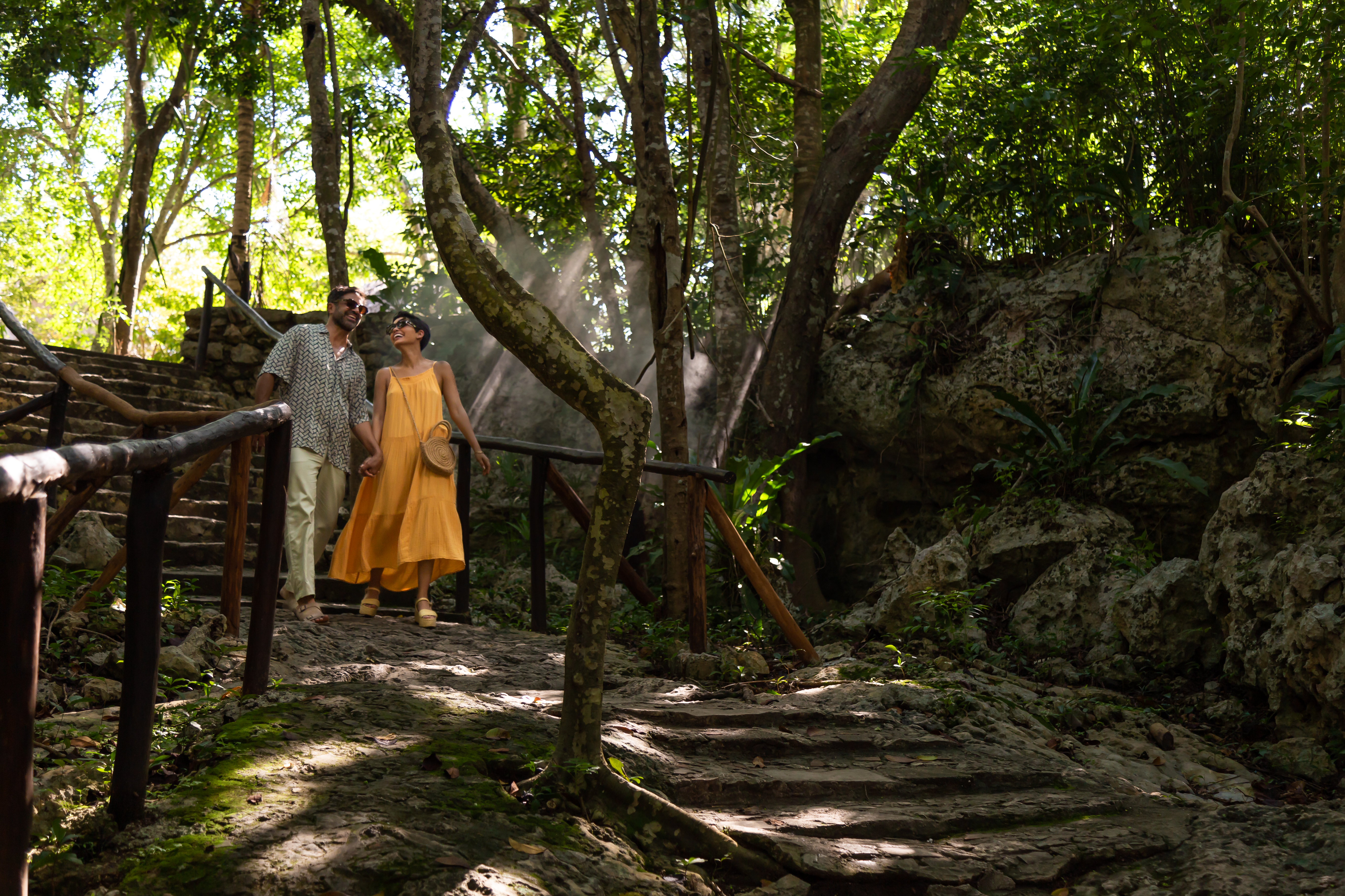 a man and woman standing on a bridge in the woods