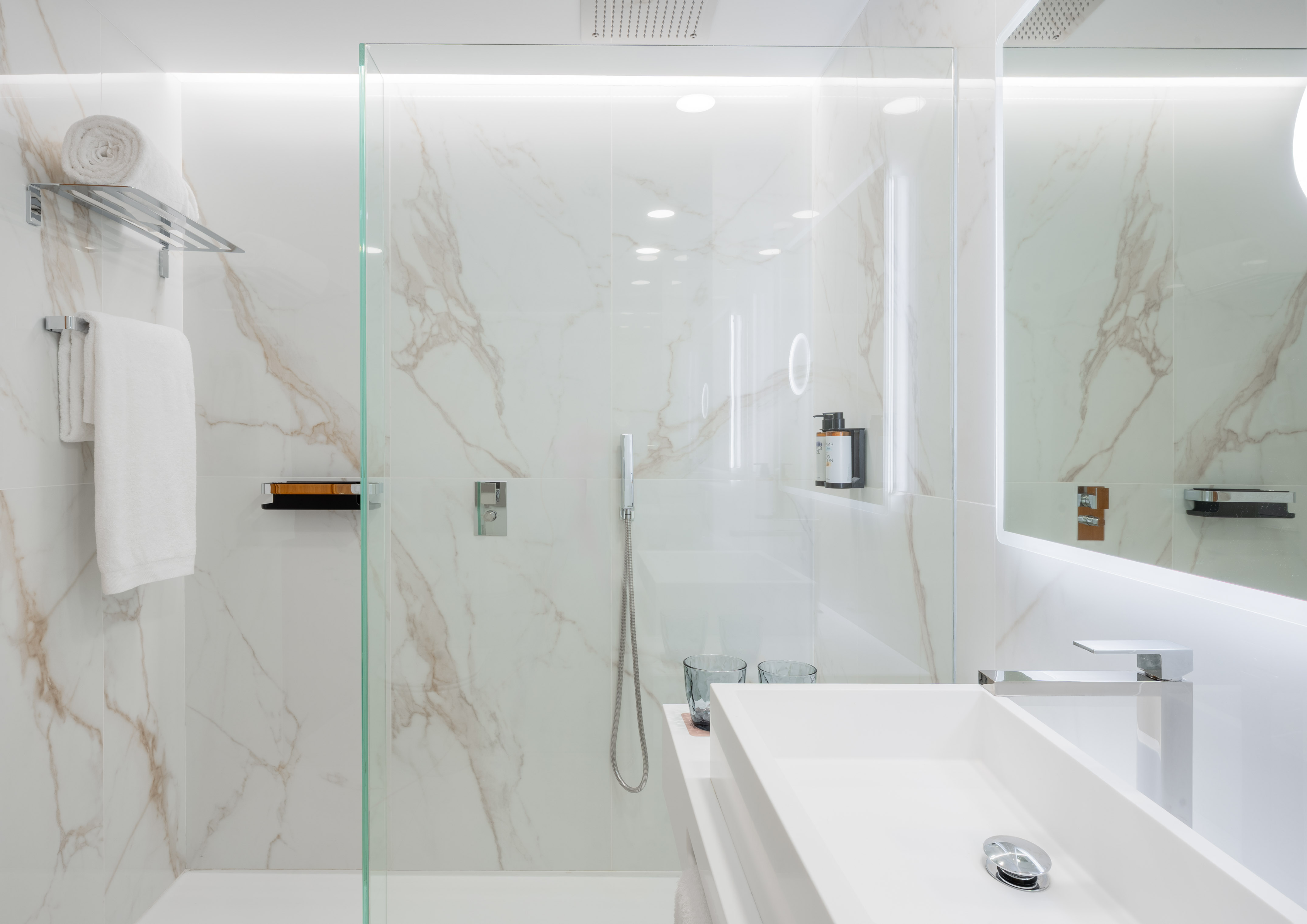 White marble bathroom with modern glass shower and vanity.