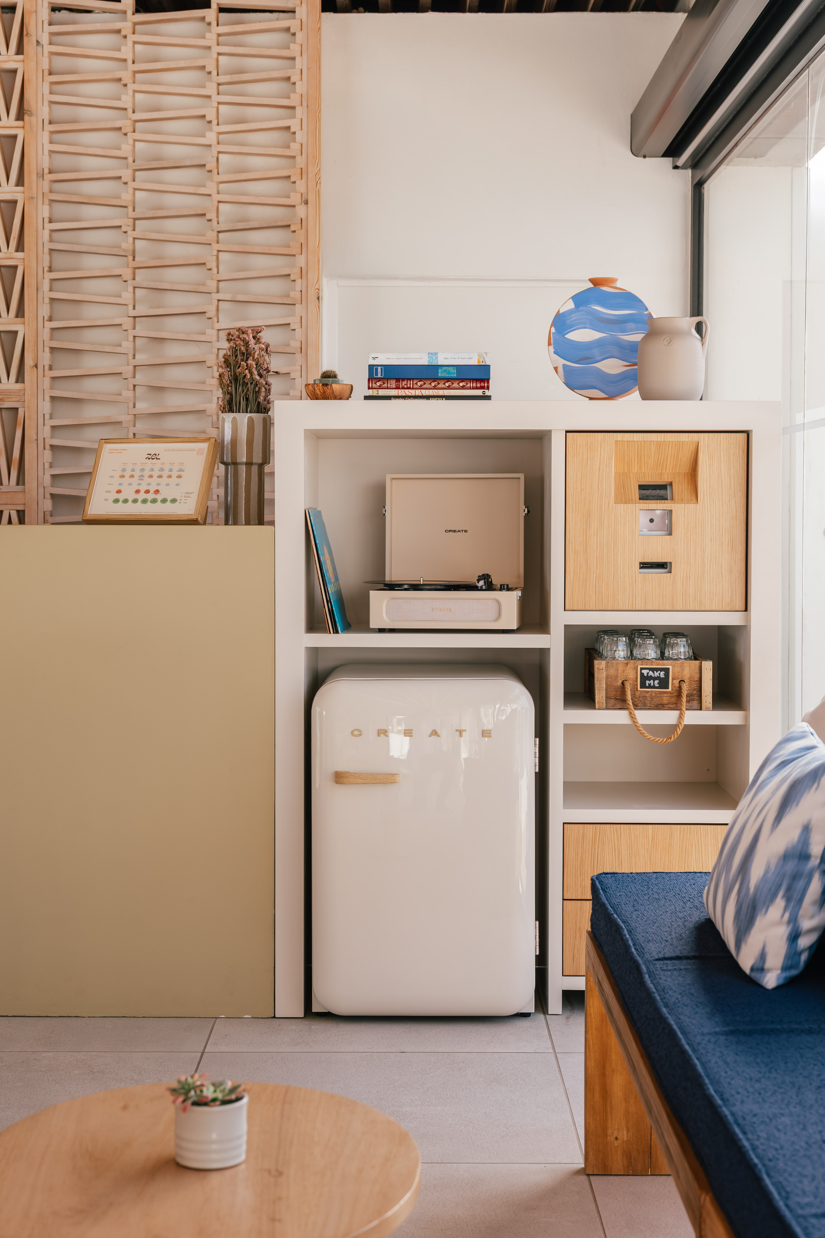 Retro record player, mini-fridge, and modern decor in a bright living space.