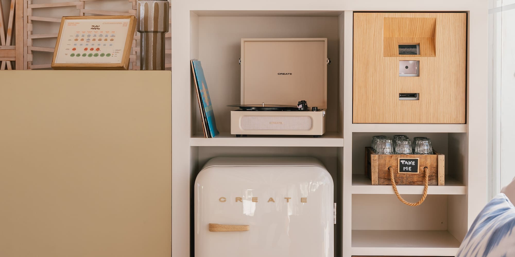 Retro record player, mini-fridge, and modern decor in a bright living space.