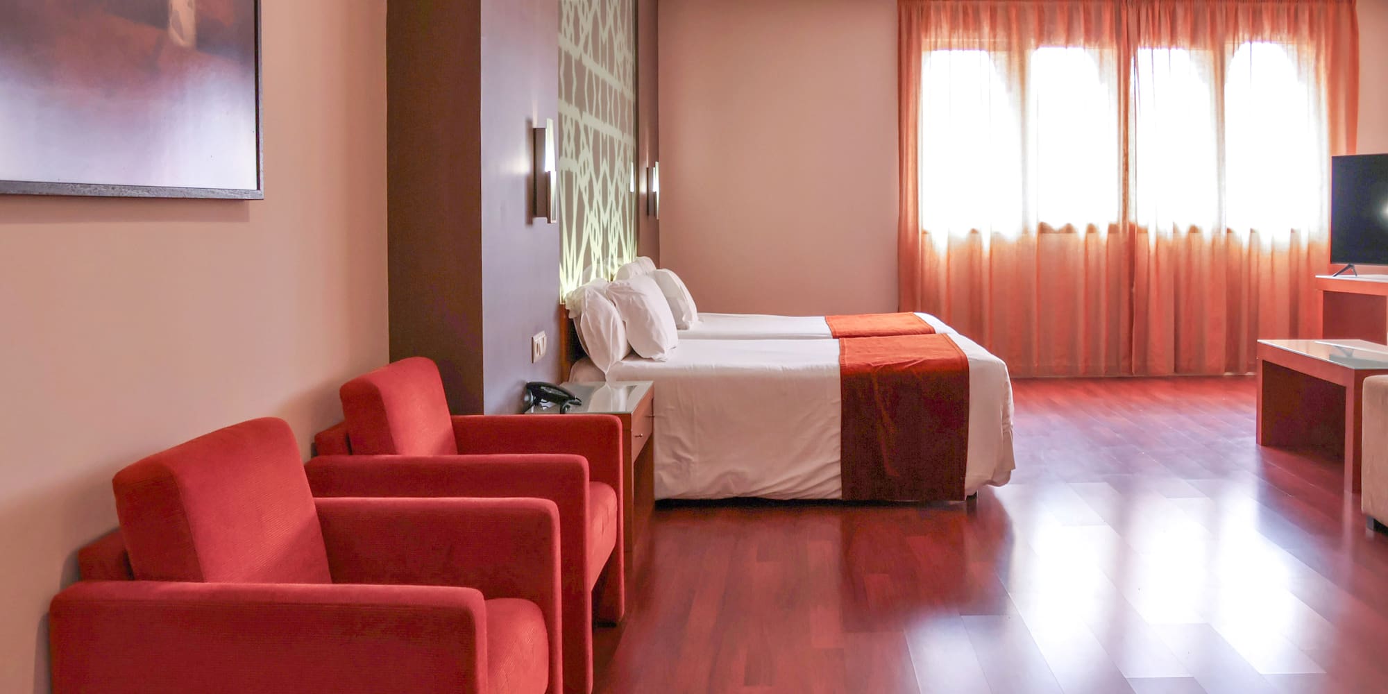 a room with two beds and red chairs