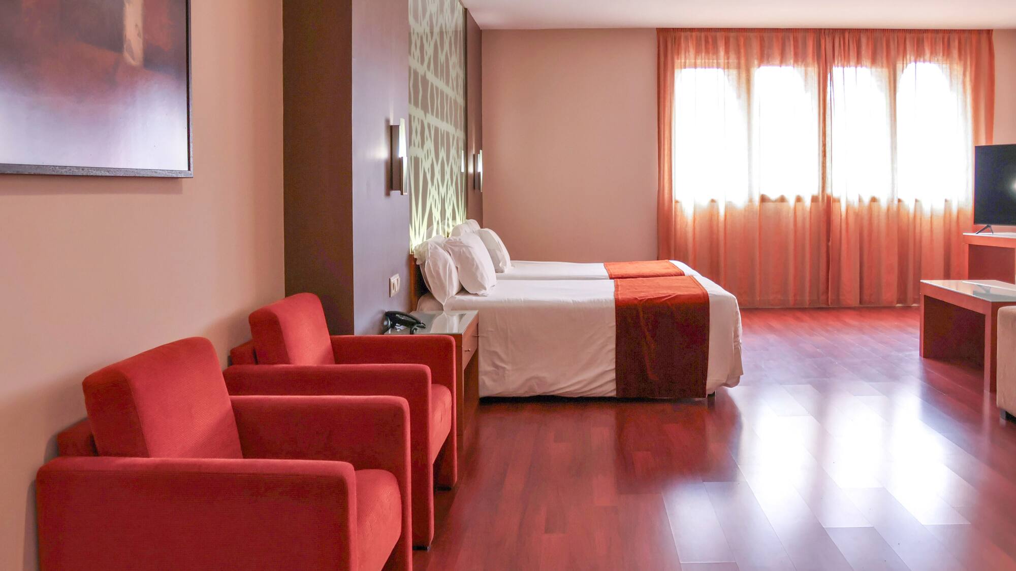 a room with two beds and red chairs