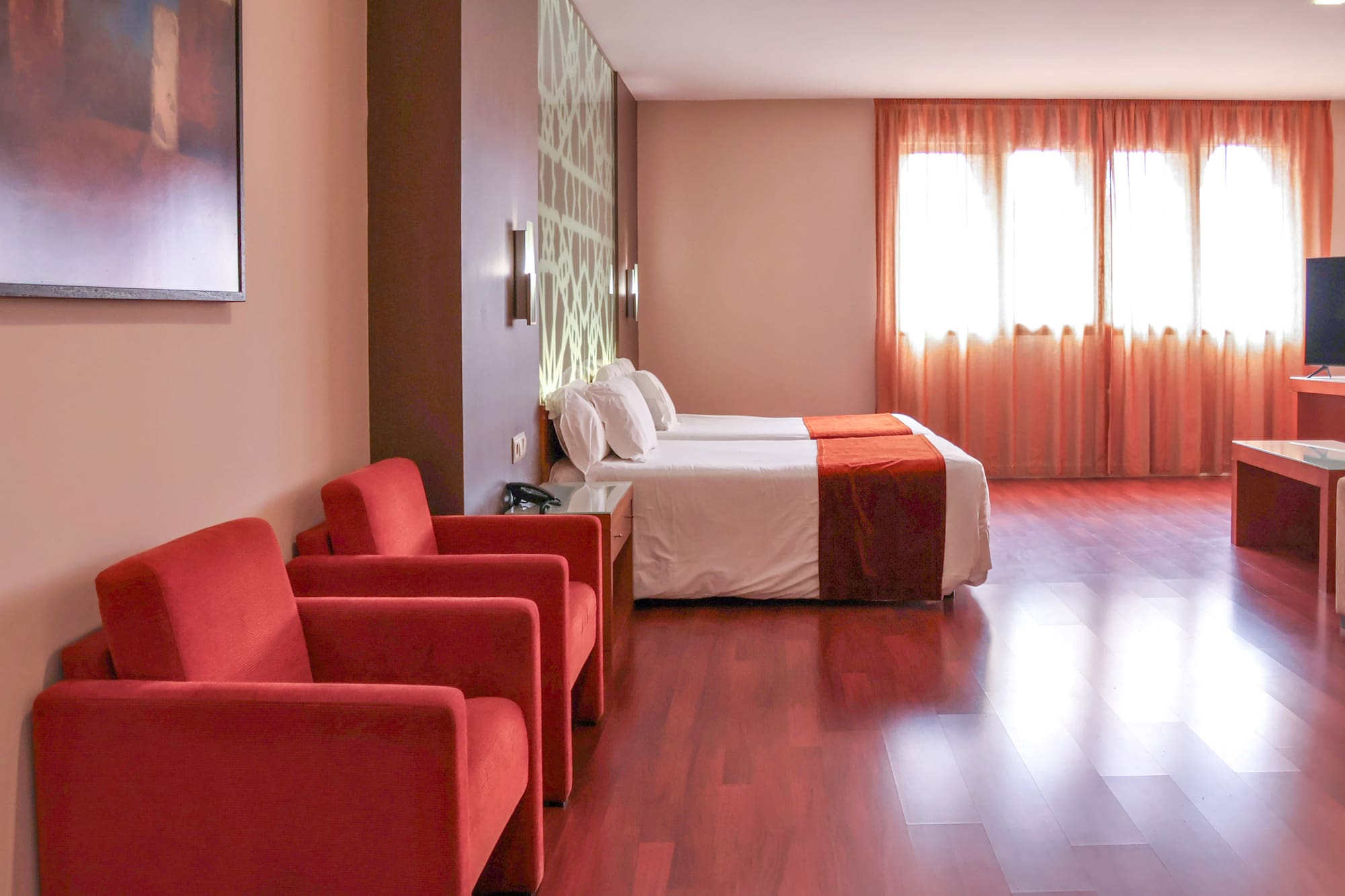 a room with two beds and red chairs