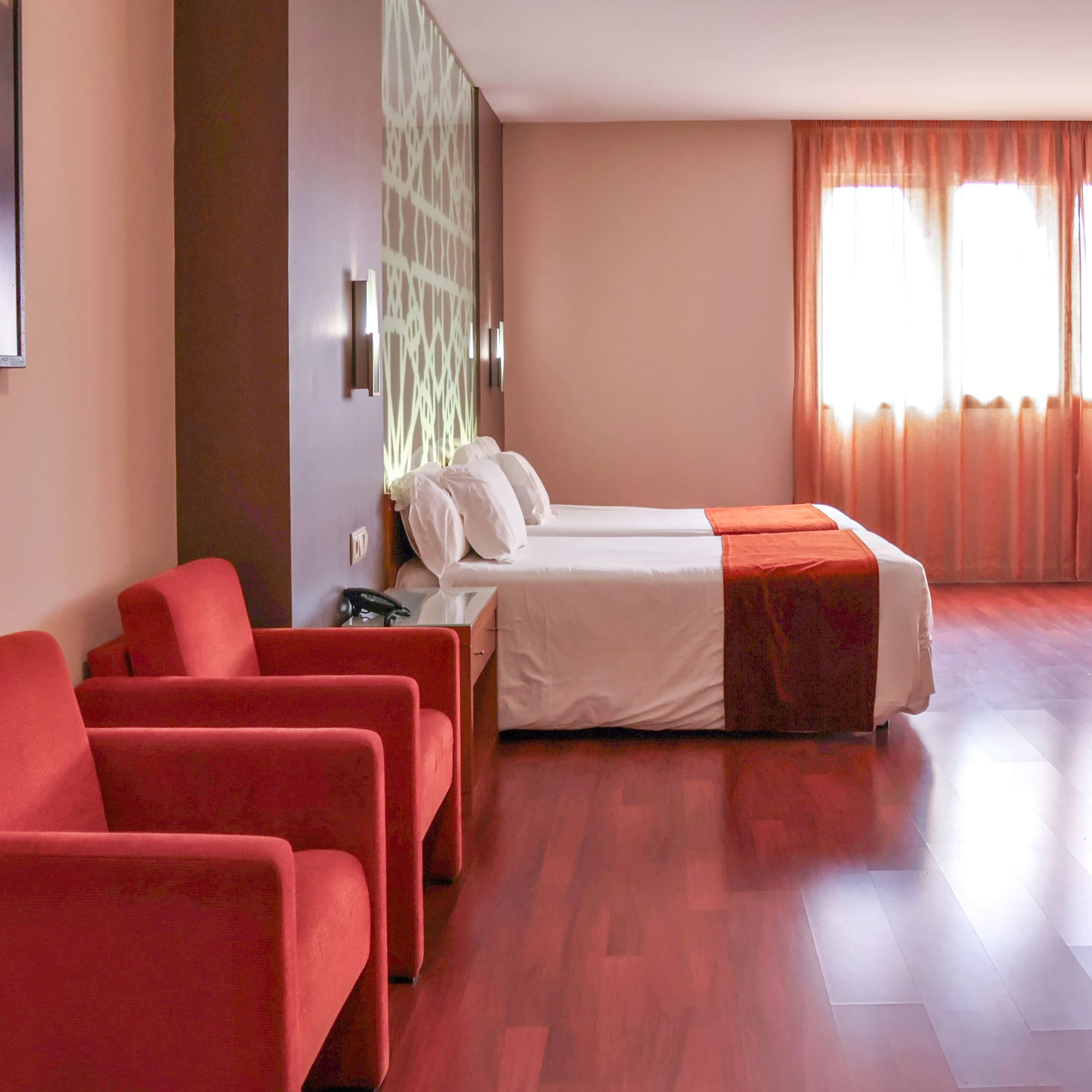 a room with two beds and red chairs