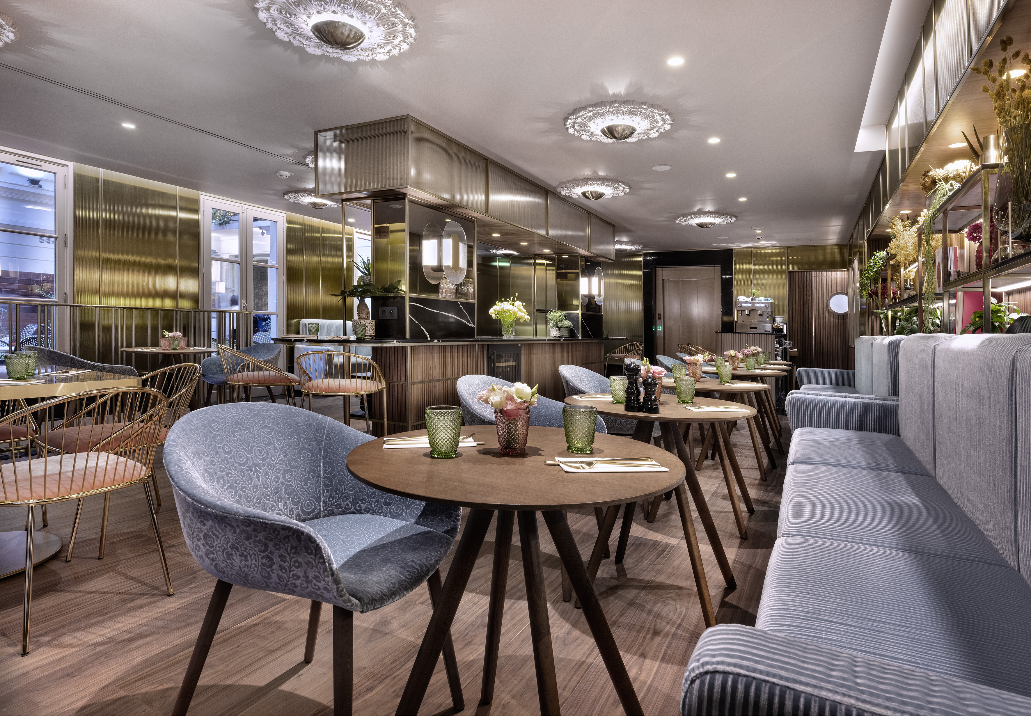 Elegant restaurant dining room with blue chairs, wood tables, and gold decor.