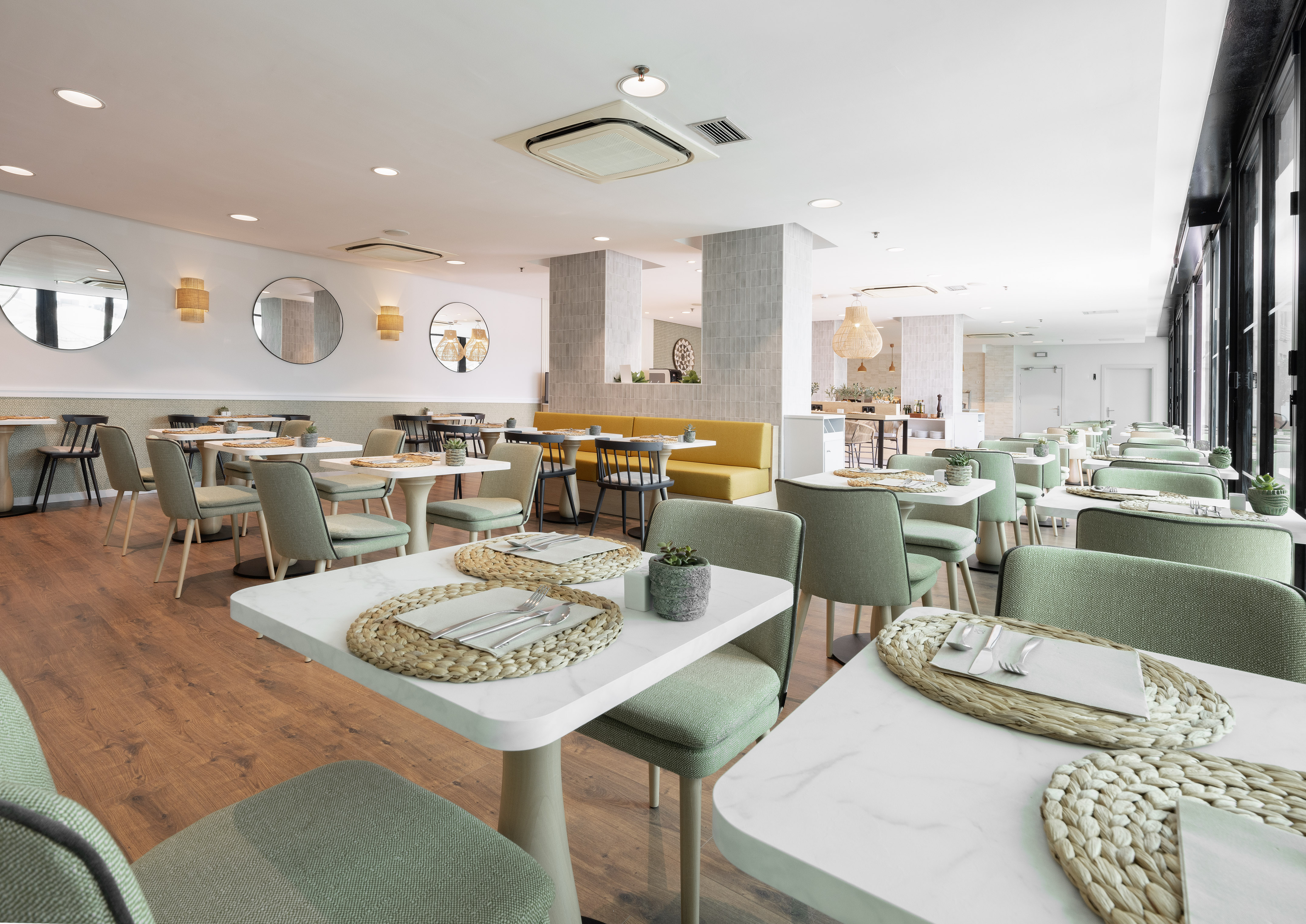 Bright modern restaurant with green chairs, white tables, and yellow booths.