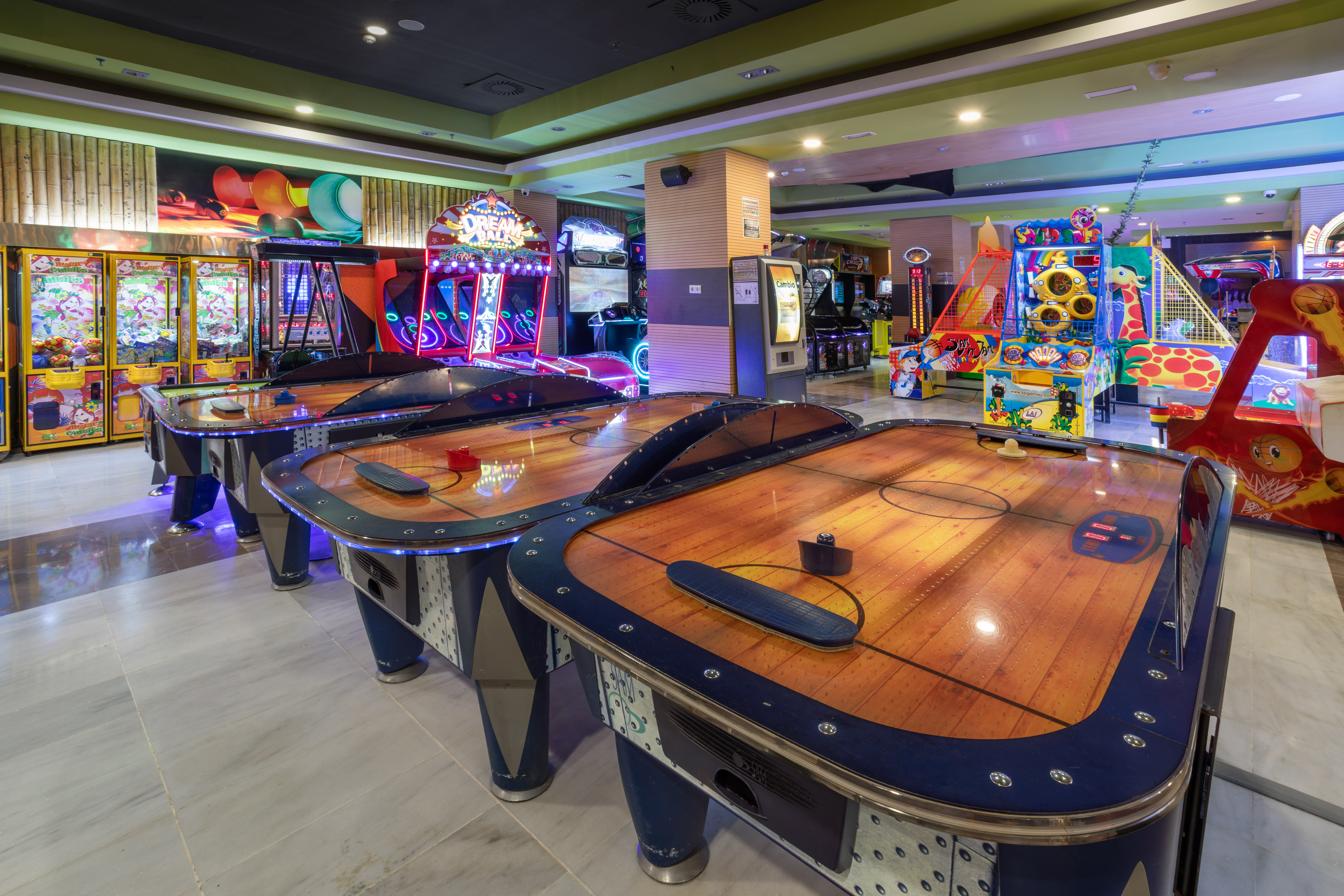 Bright arcade with air hockey tables, claw machines, and various games.