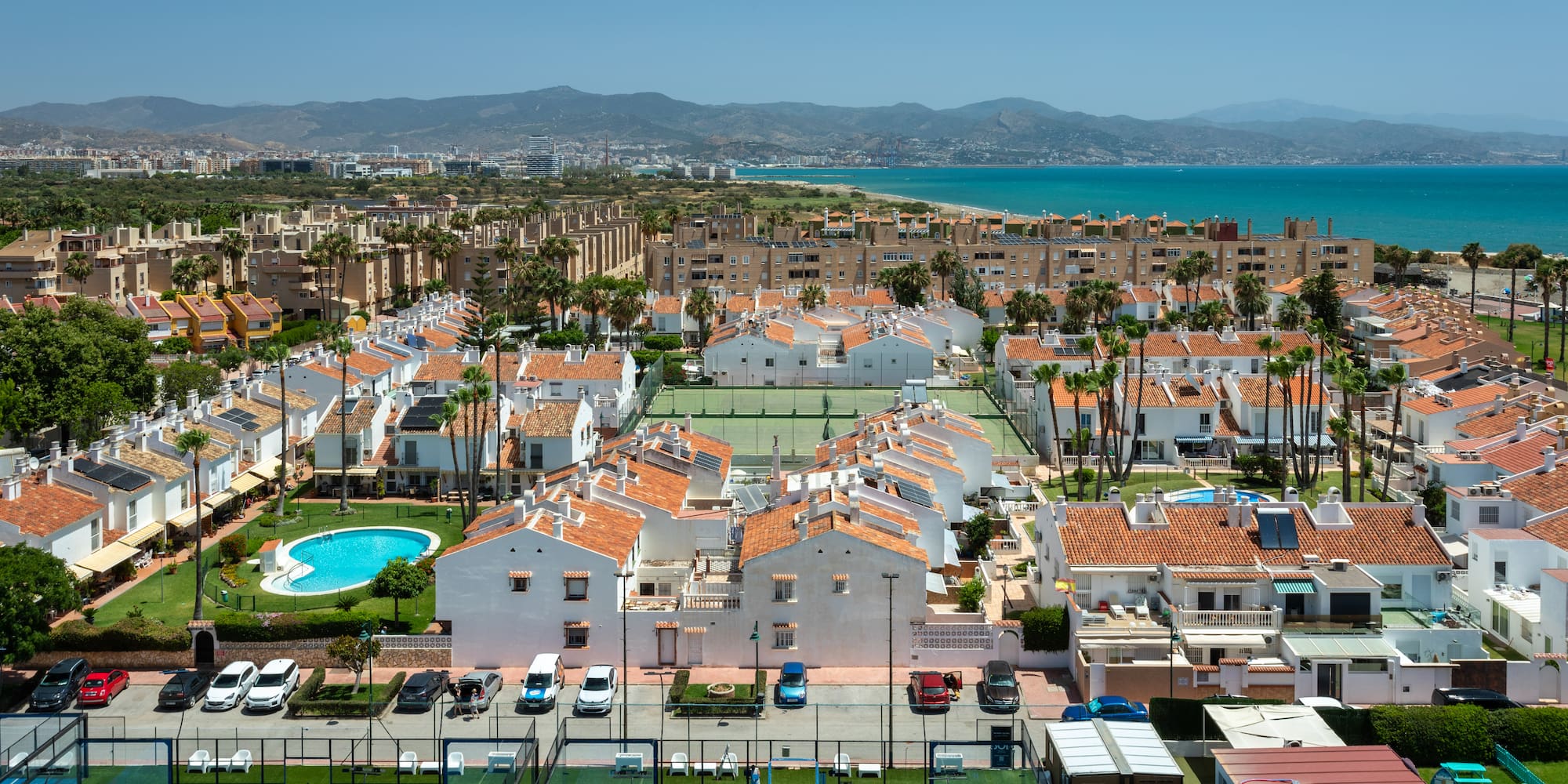 Urbanización costera con casas, piscinas, pádel, tenis y mar Mediterráneo.