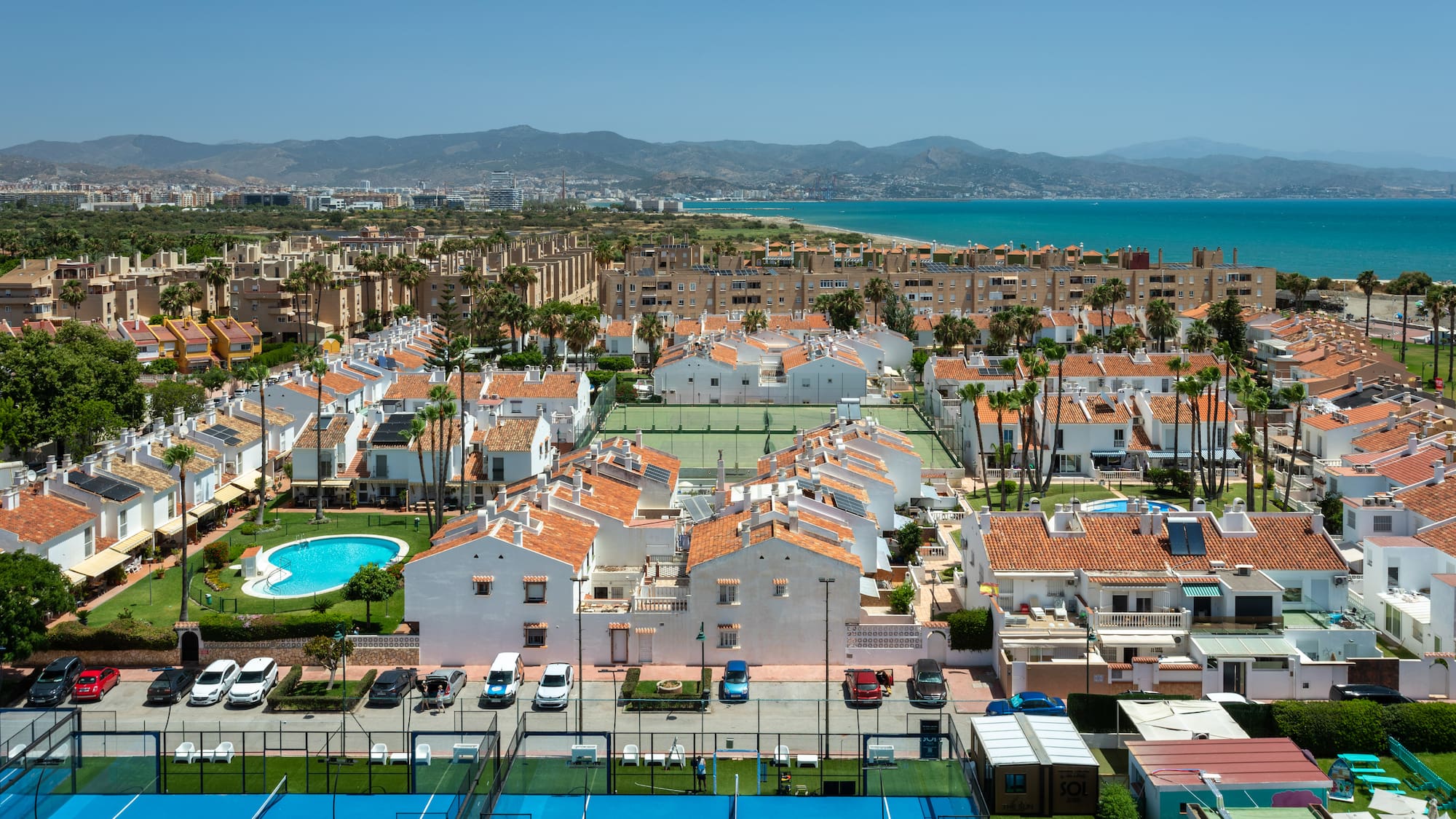 Urbanización costera con casas, piscinas, pádel, tenis y mar Mediterráneo.