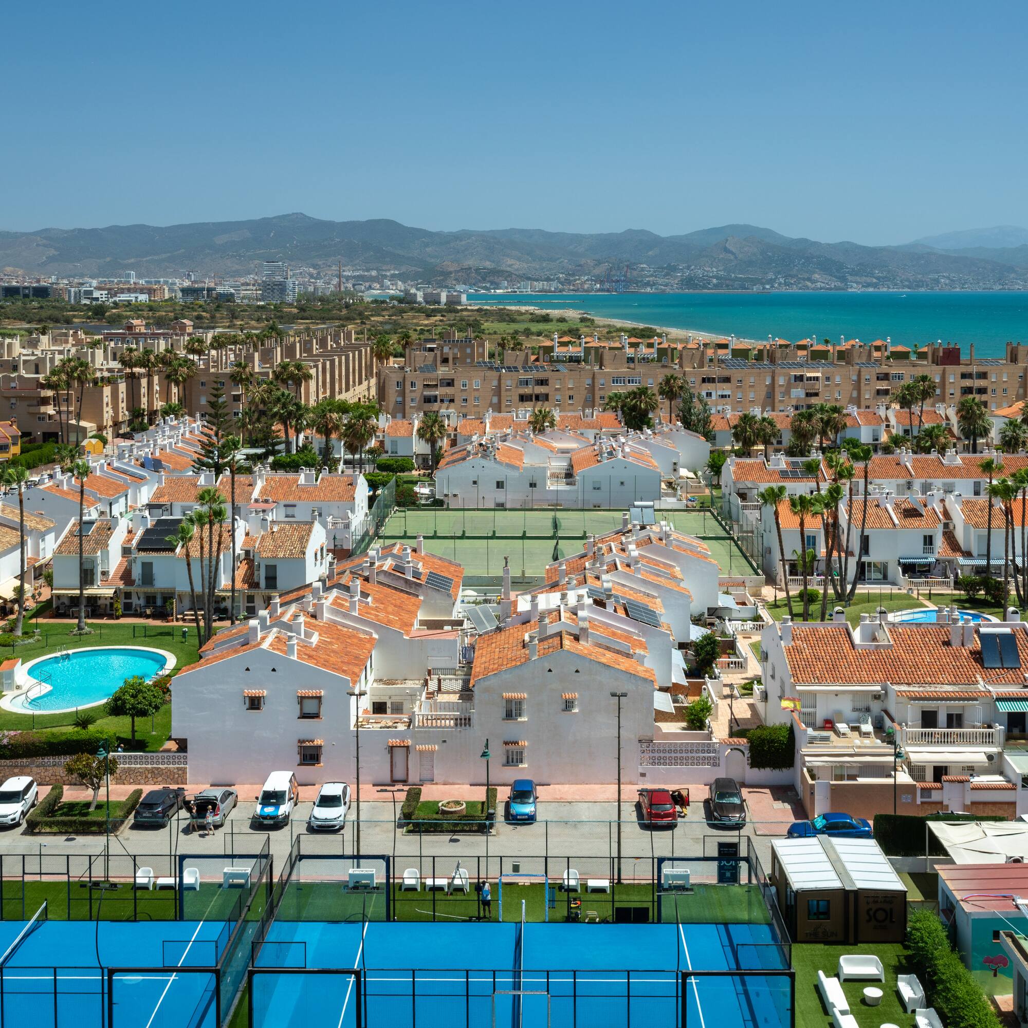 Urbanización costera con casas, piscinas, pádel, tenis y mar Mediterráneo.