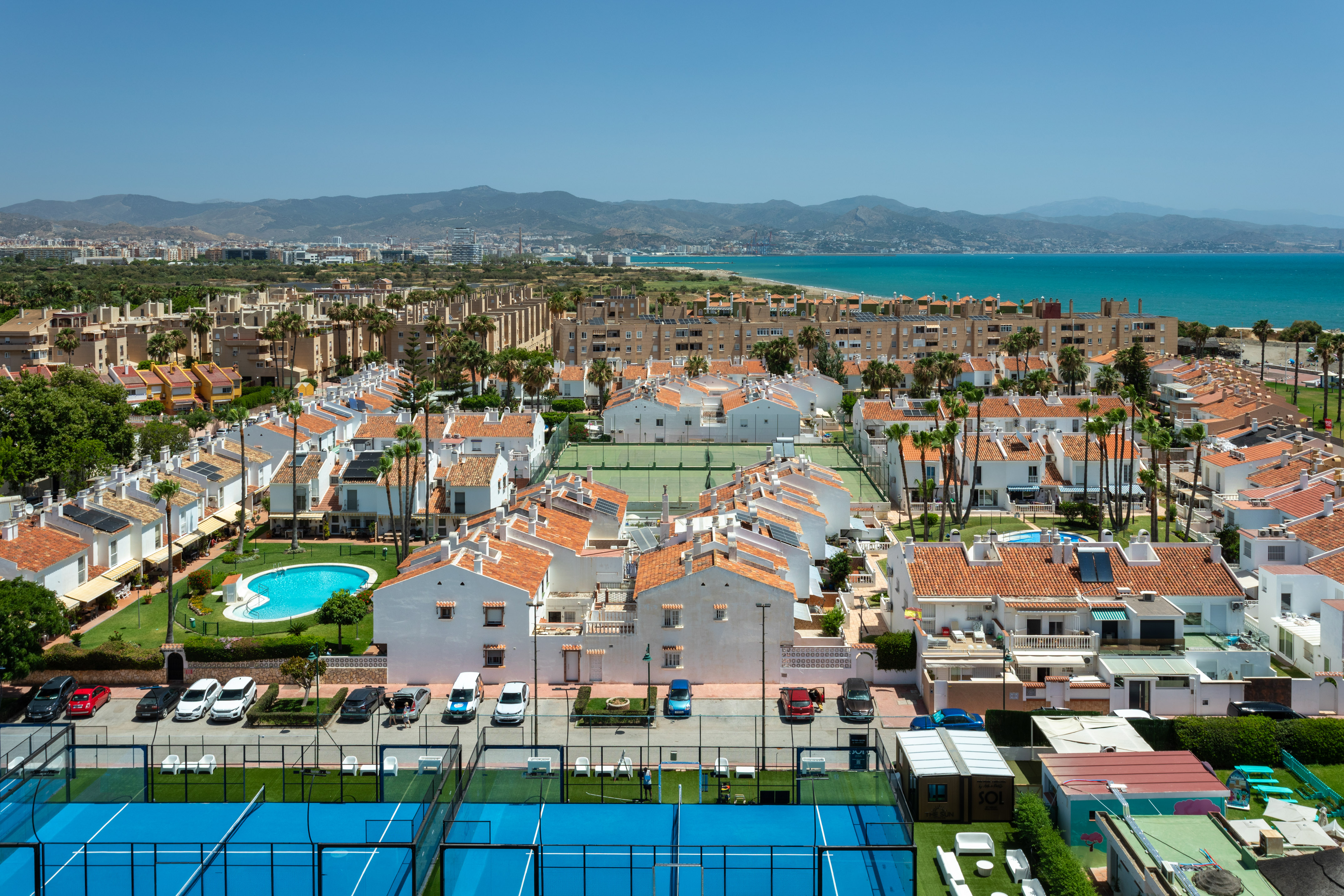 Urbanización costera con casas, piscinas, pádel, tenis y mar Mediterráneo.