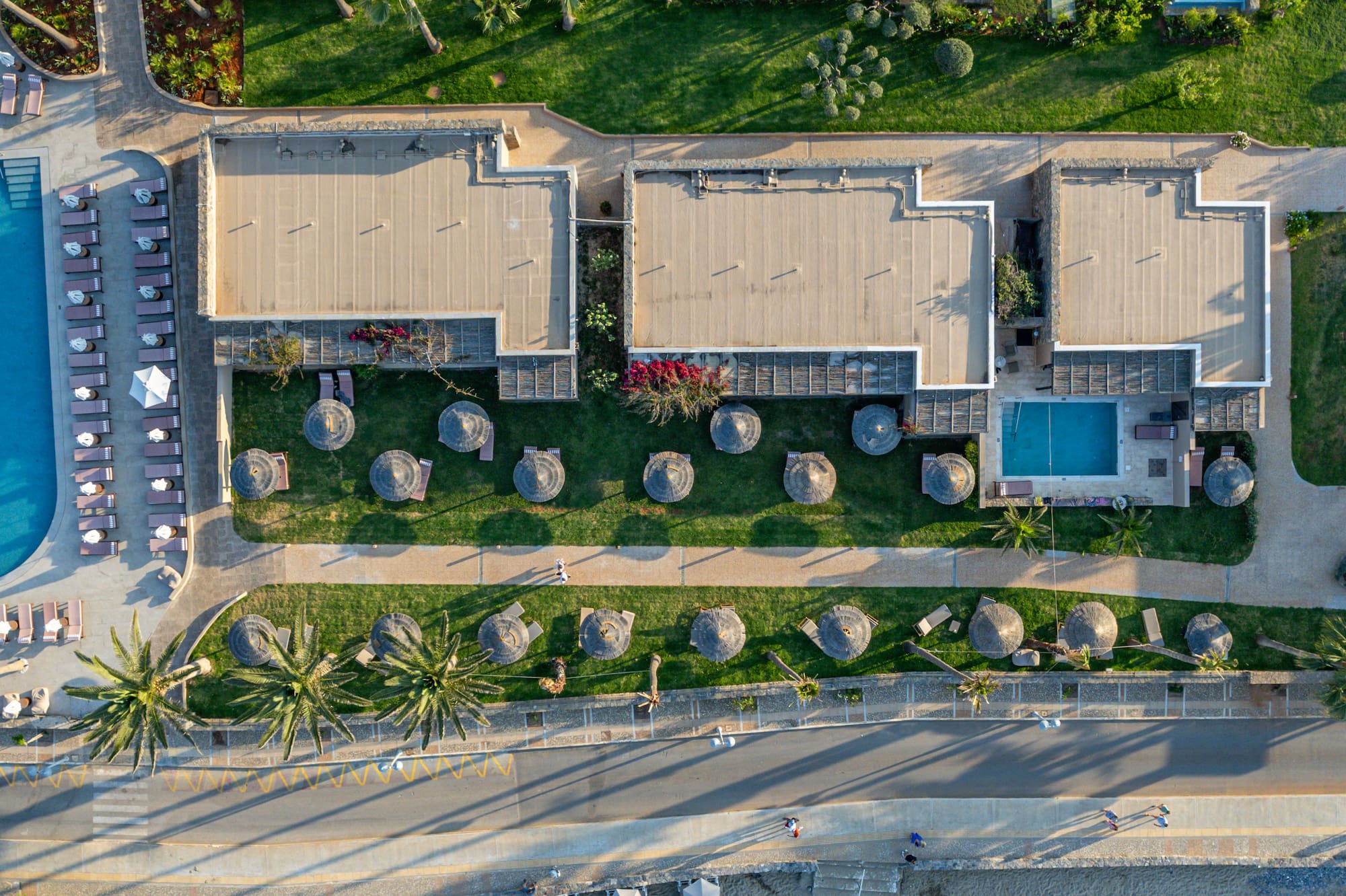 Aerial view of luxury beach resort with private pools, palm trees, and ocean.
