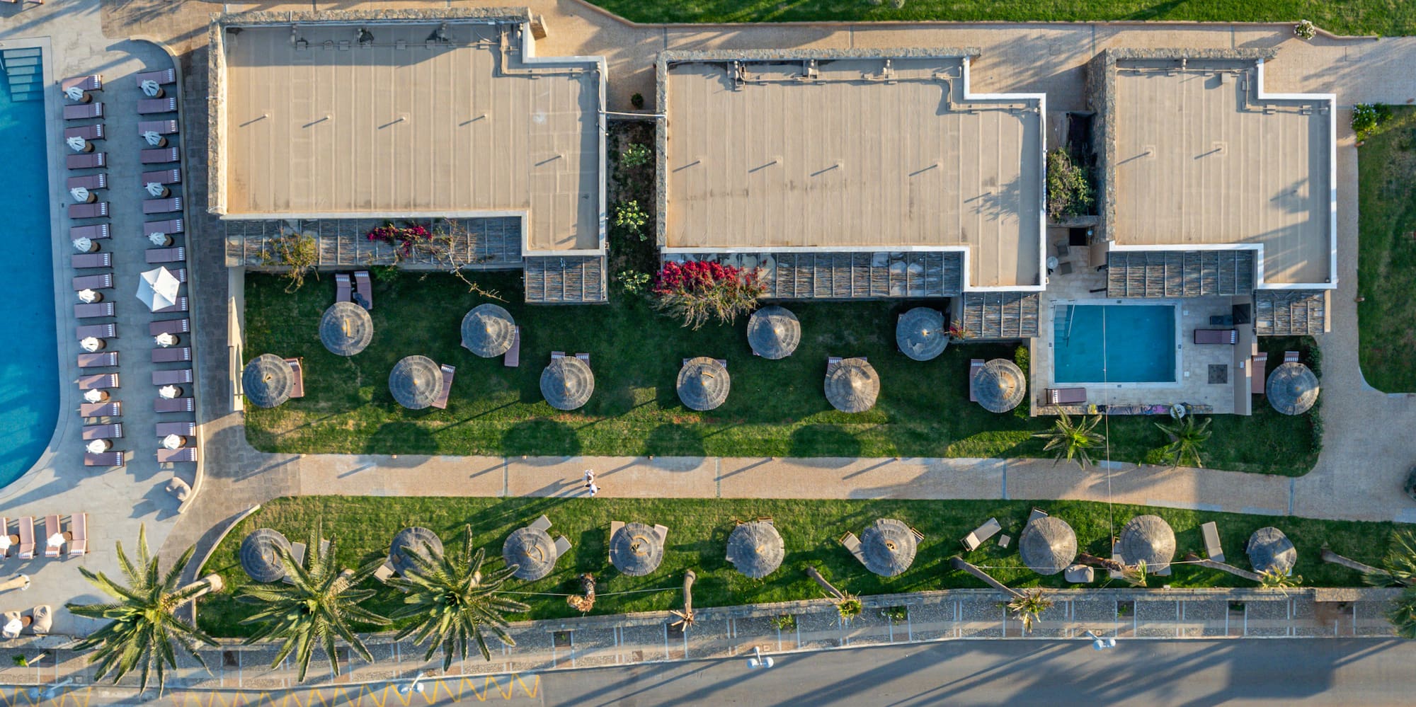 Aerial view of luxury beach resort with private pools, palm trees, and ocean.