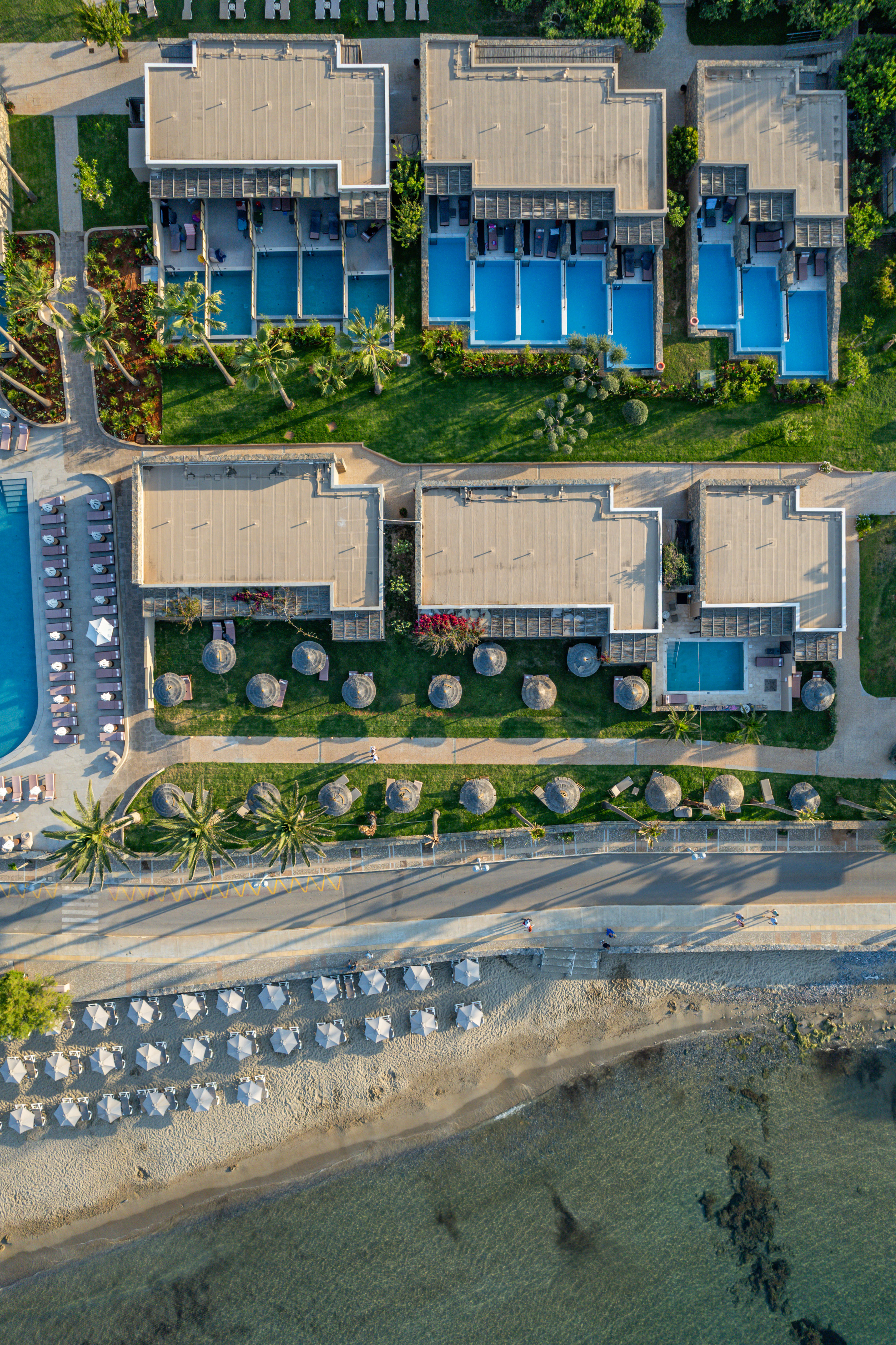 Aerial view of luxury beach resort with private pools, palm trees, and ocean.