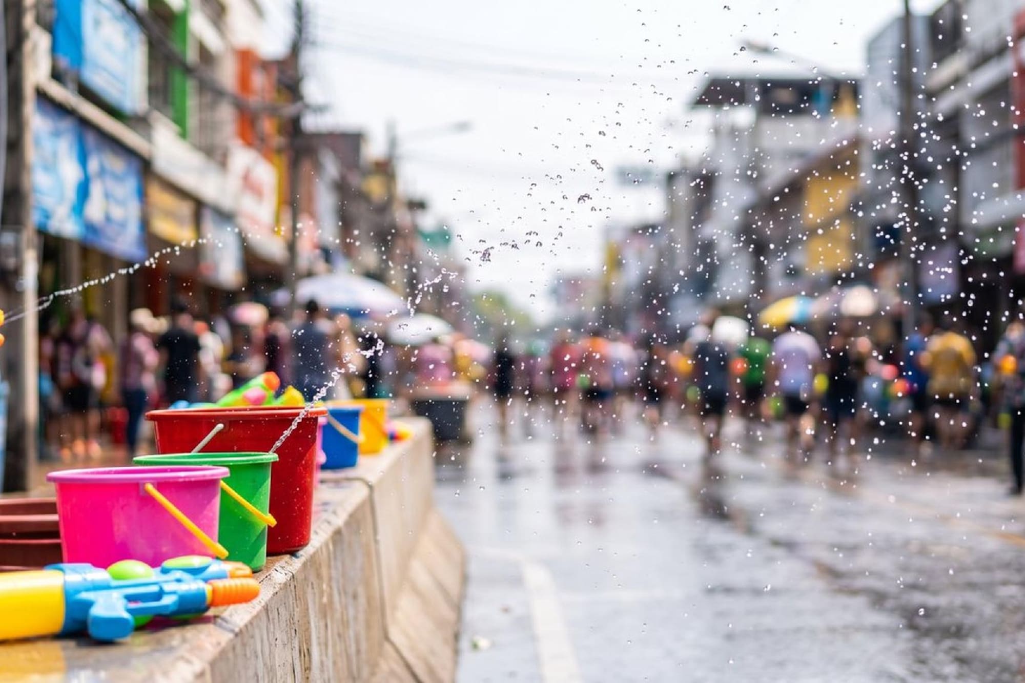 Colorful water guns and buckets on a wet street during Songkran festival.
