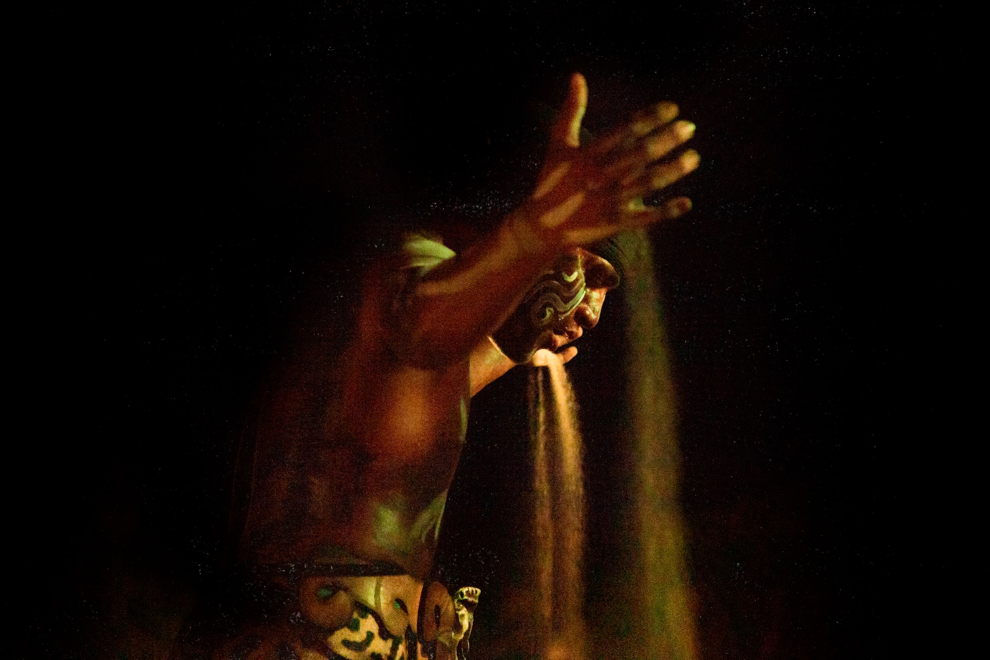 a man with a face paint pouring sand out of his hand