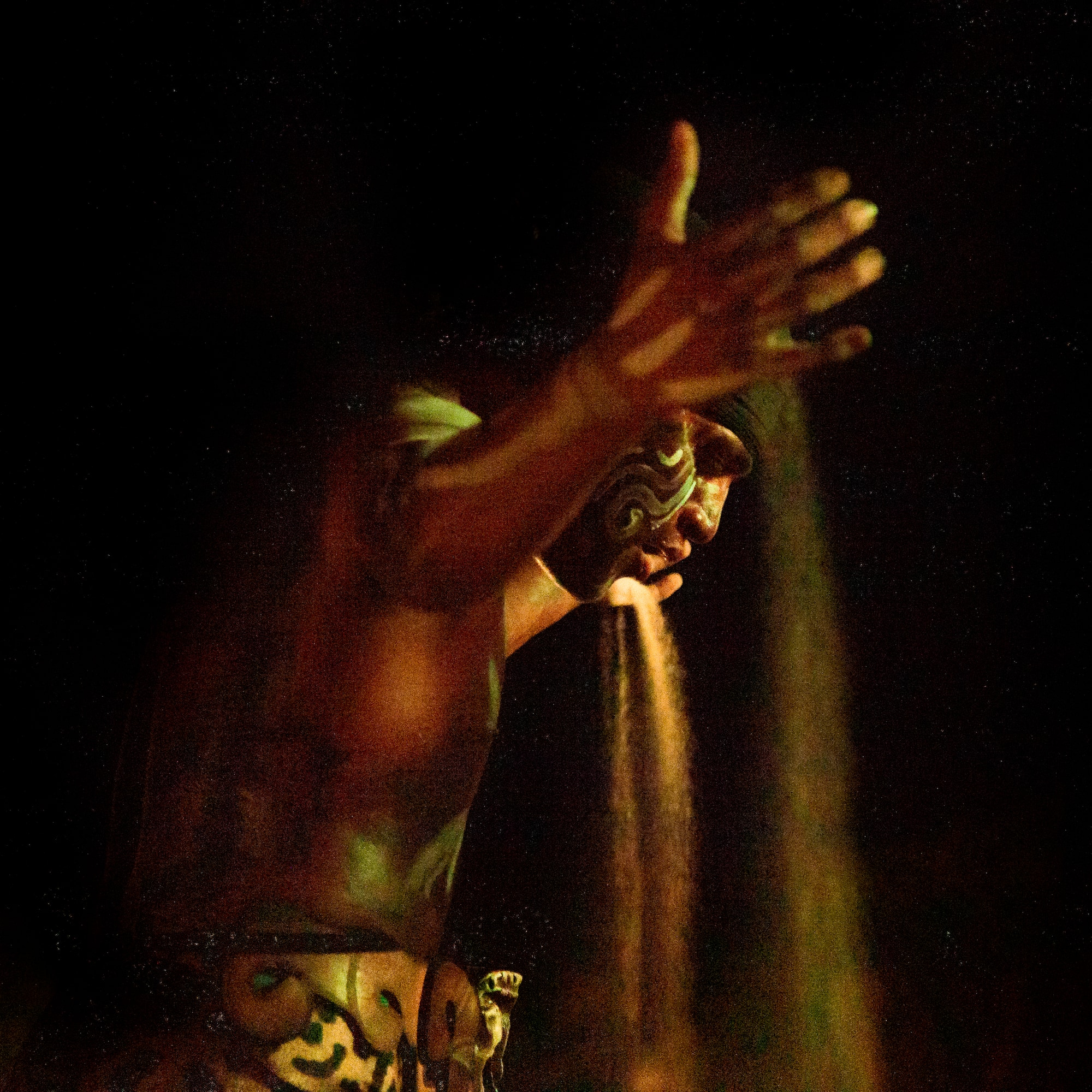 a man with a face paint pouring sand out of his hand