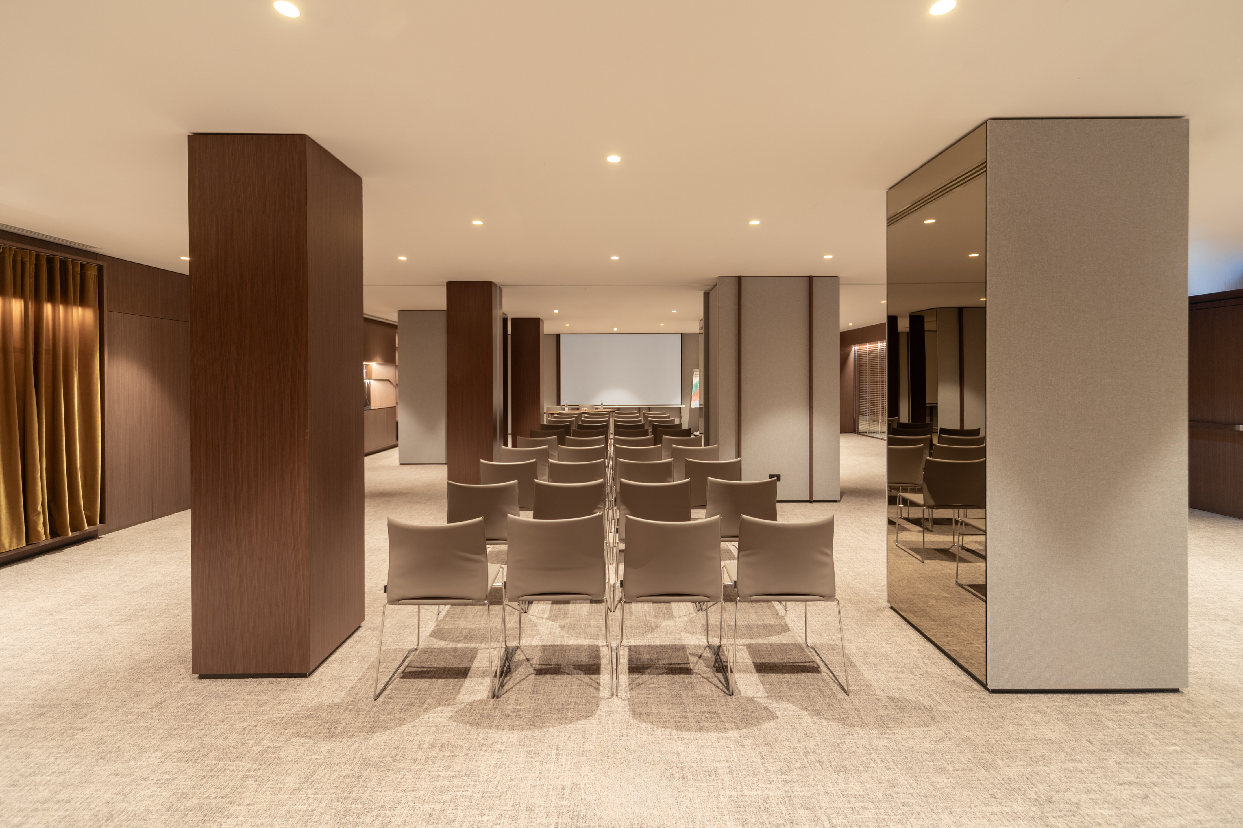 Modern conference room with rows of chairs and a large presentation screen.