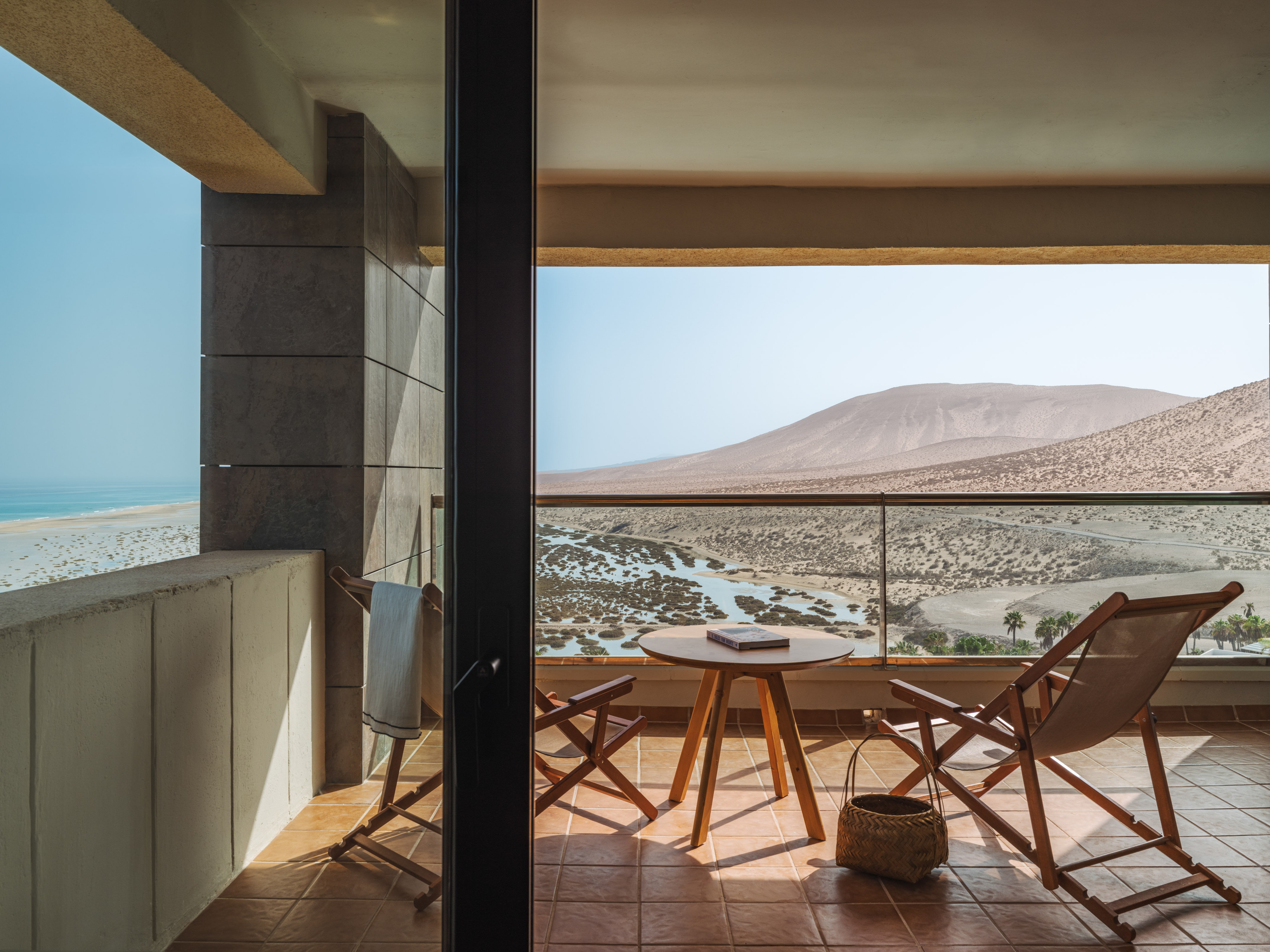 Resort balcony with desert, ocean, and estuary views; chairs and table.