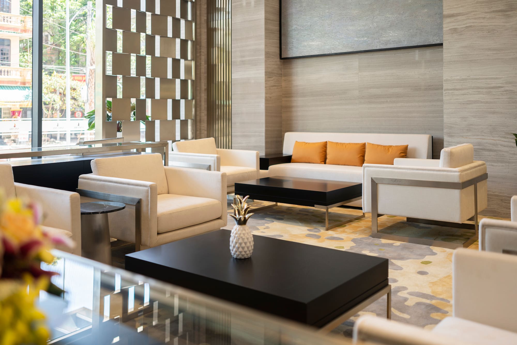 Modern hotel lobby lounge with cream seating, black tables, and patterned rug.