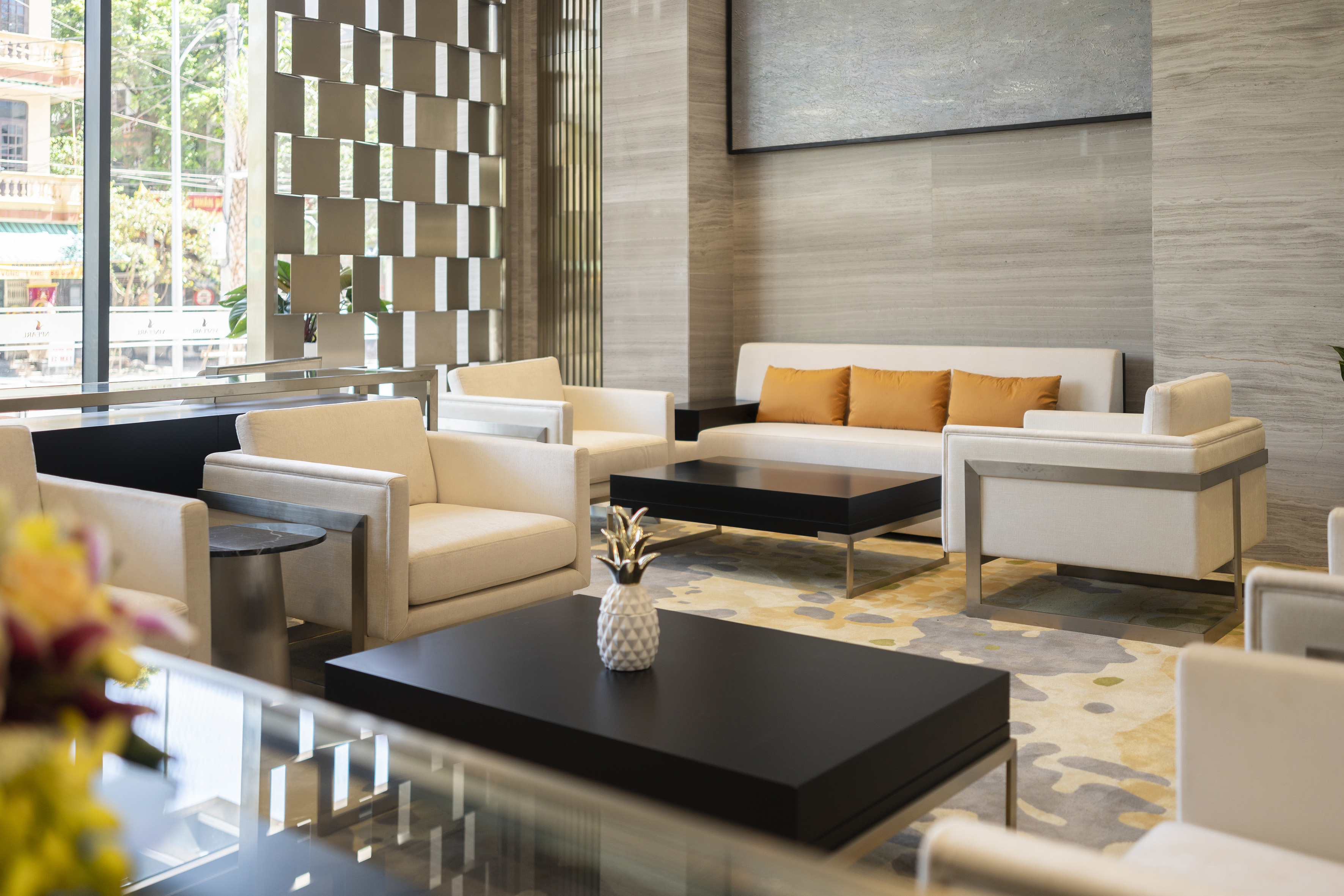 Modern hotel lobby lounge with cream seating, black tables, and patterned rug.