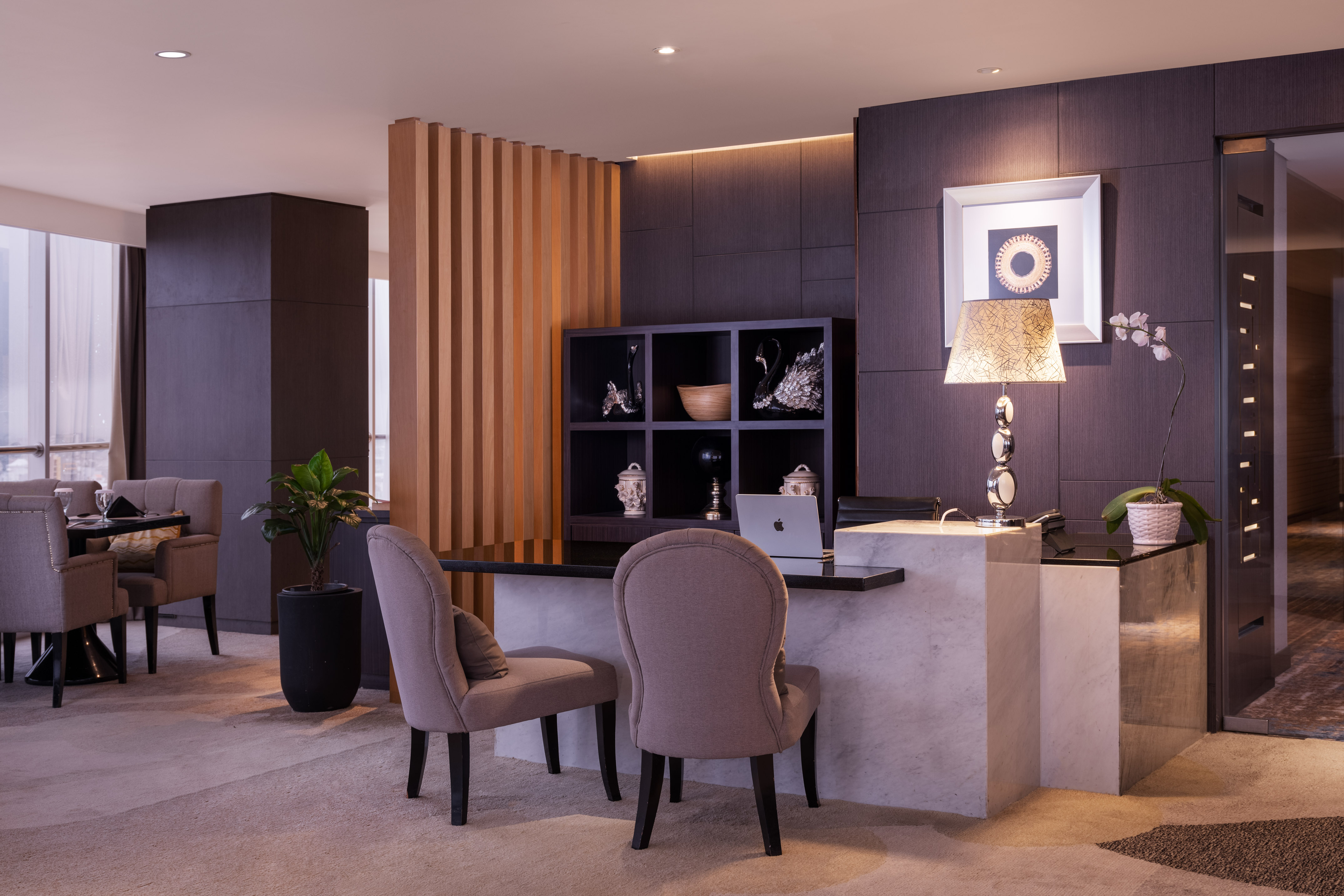 Elegant modern reception desk with marble counter, wood slats, and plush chairs.