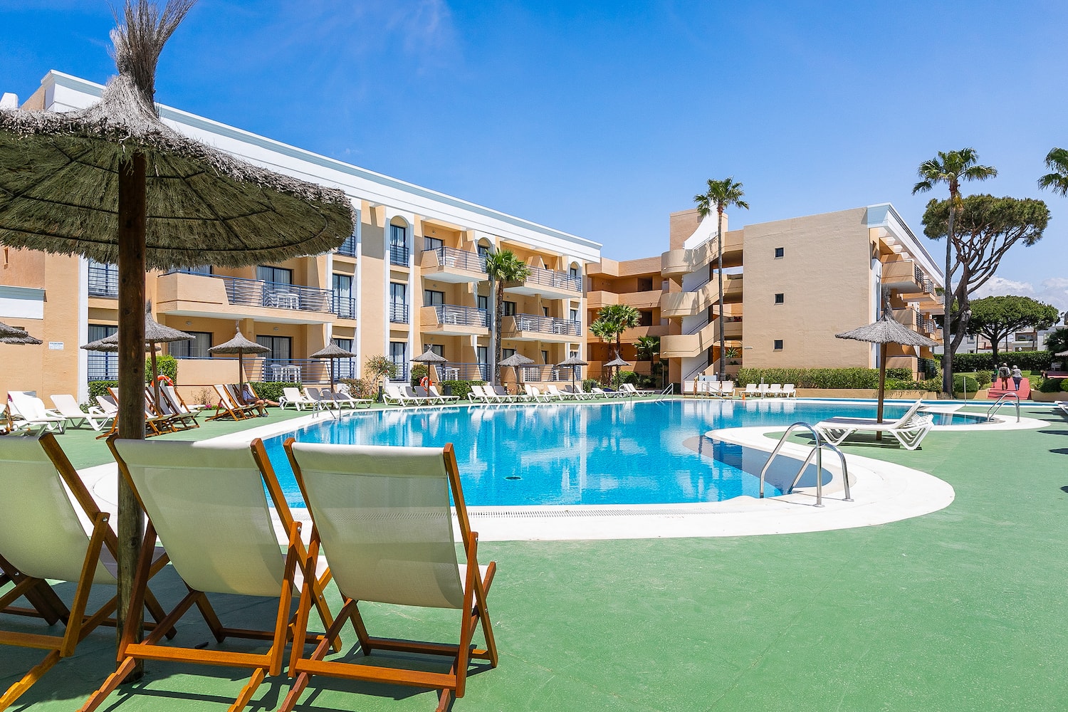 a pool with chairs and umbrellas in front of a building