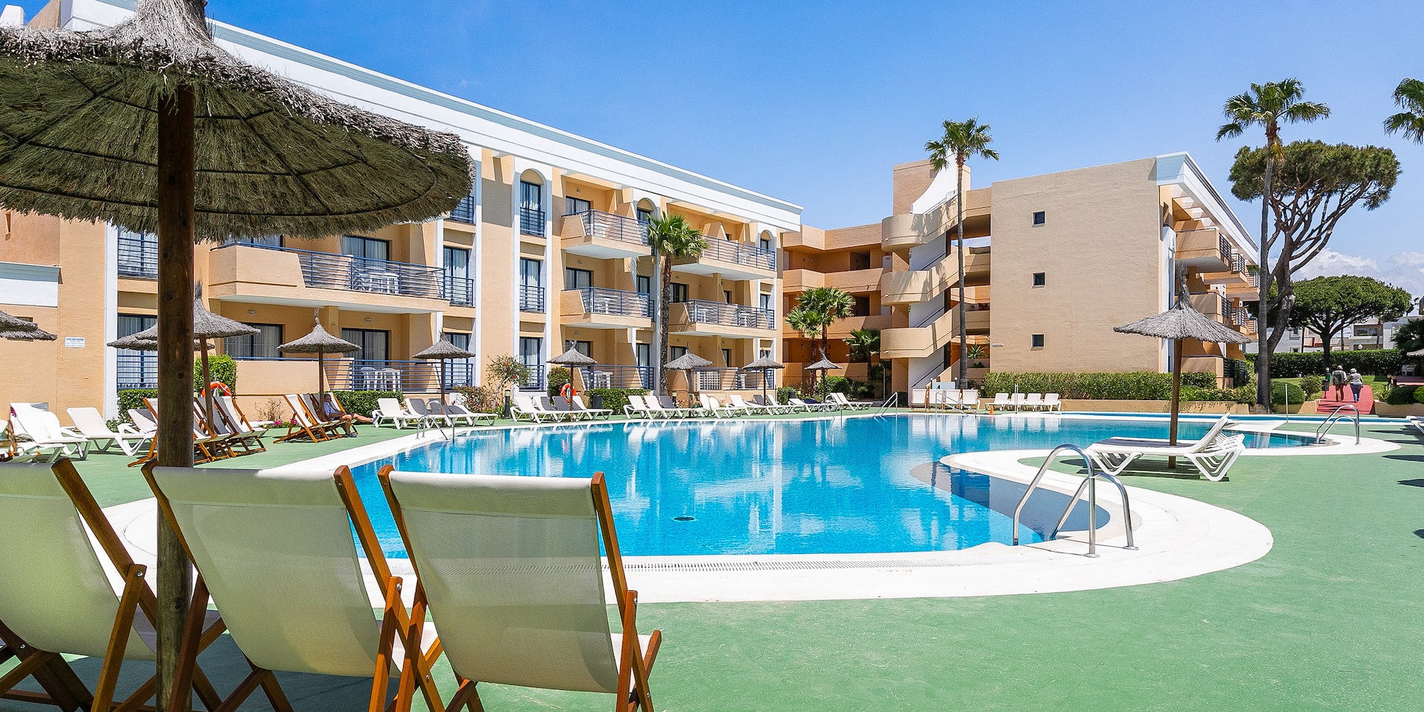 a pool with chairs and umbrellas in front of a building