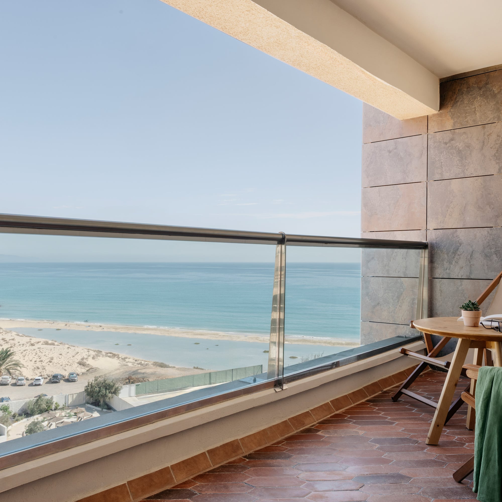 a balcony with a table and chairs and a beach view