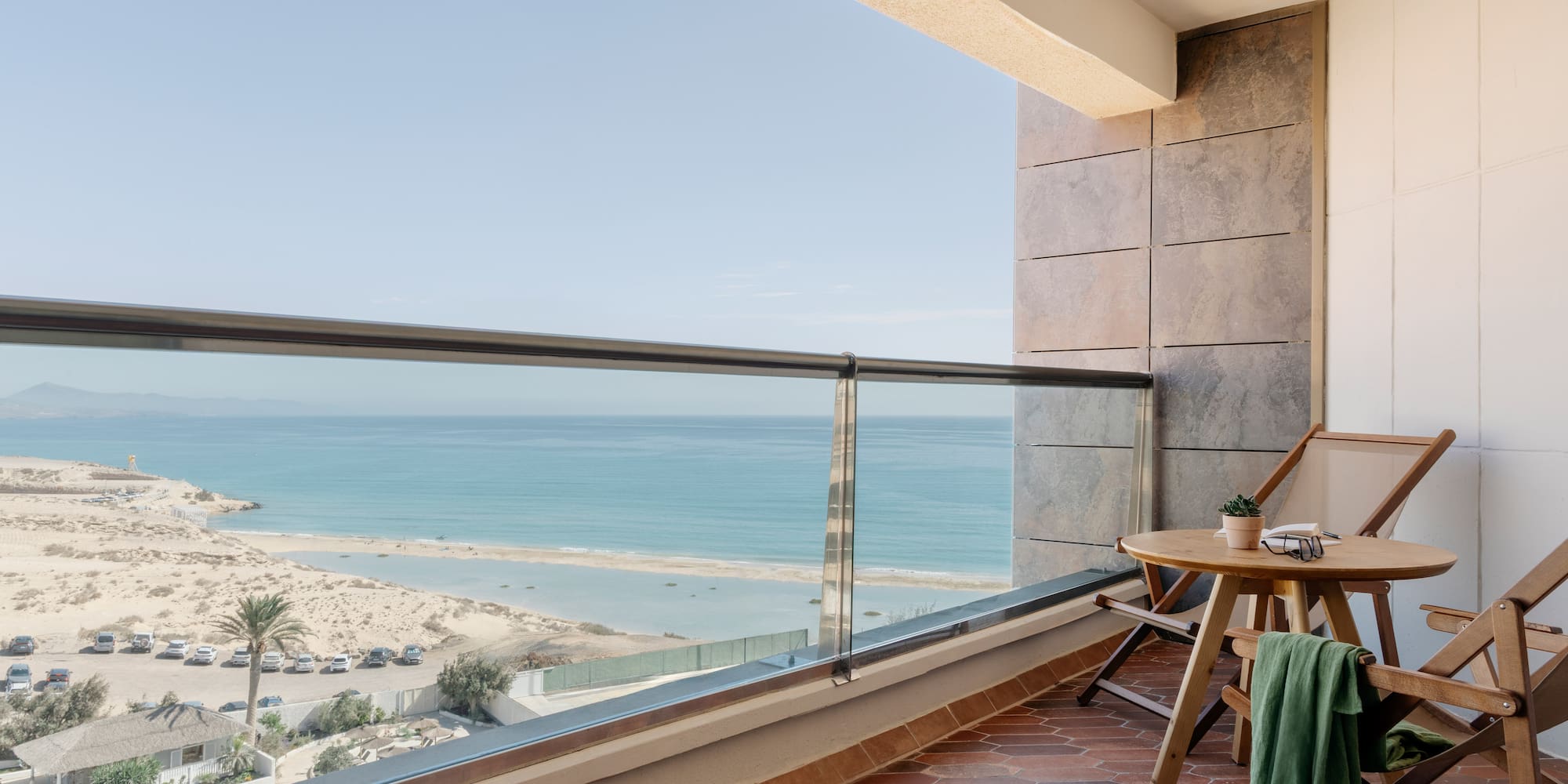 a balcony with a table and chairs and a beach view