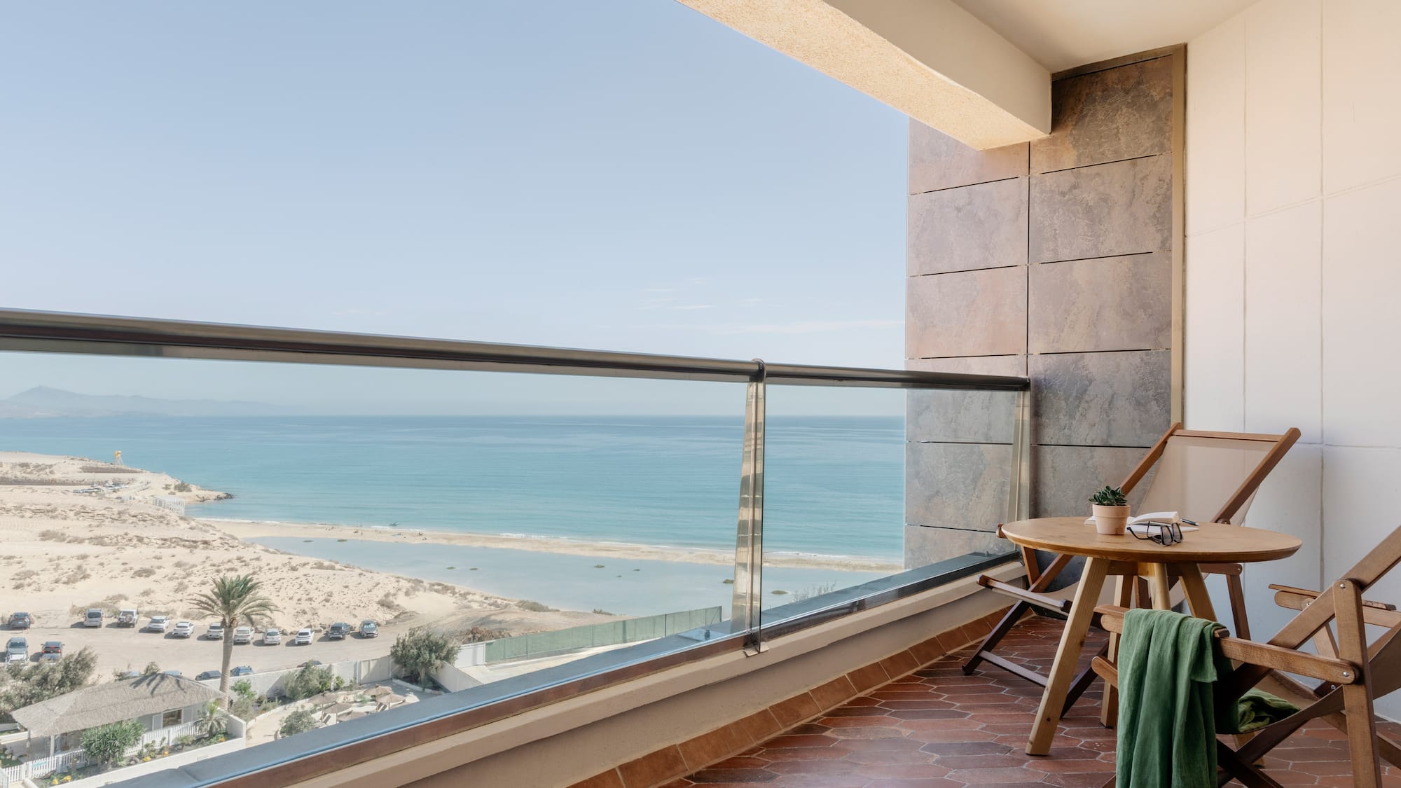 a balcony with a table and chairs and a beach view