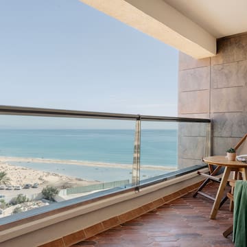 a balcony with a table and chairs and a beach view