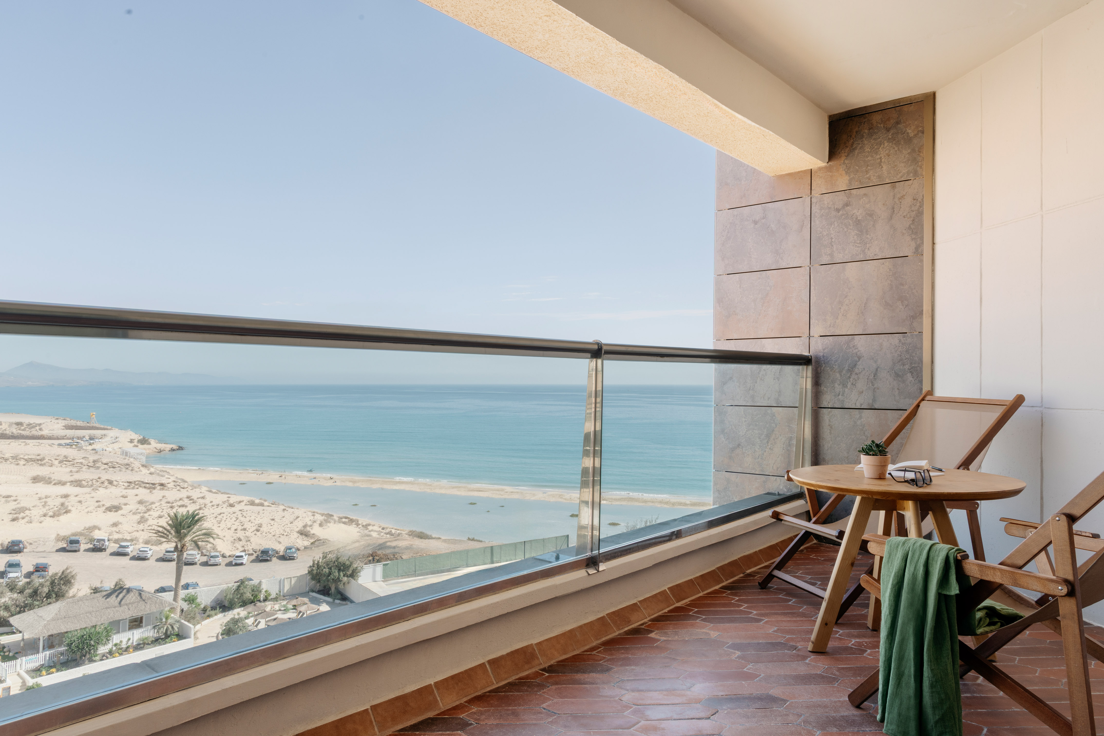 a balcony with a table and chairs and a beach view