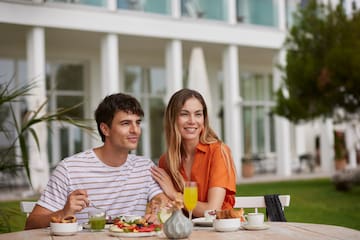 a man and woman sitting at a table with food and drinks