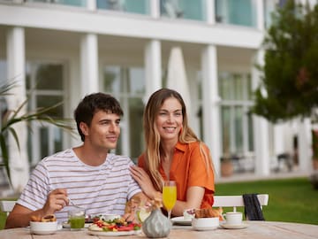 a man and woman sitting at a table with food and drinks