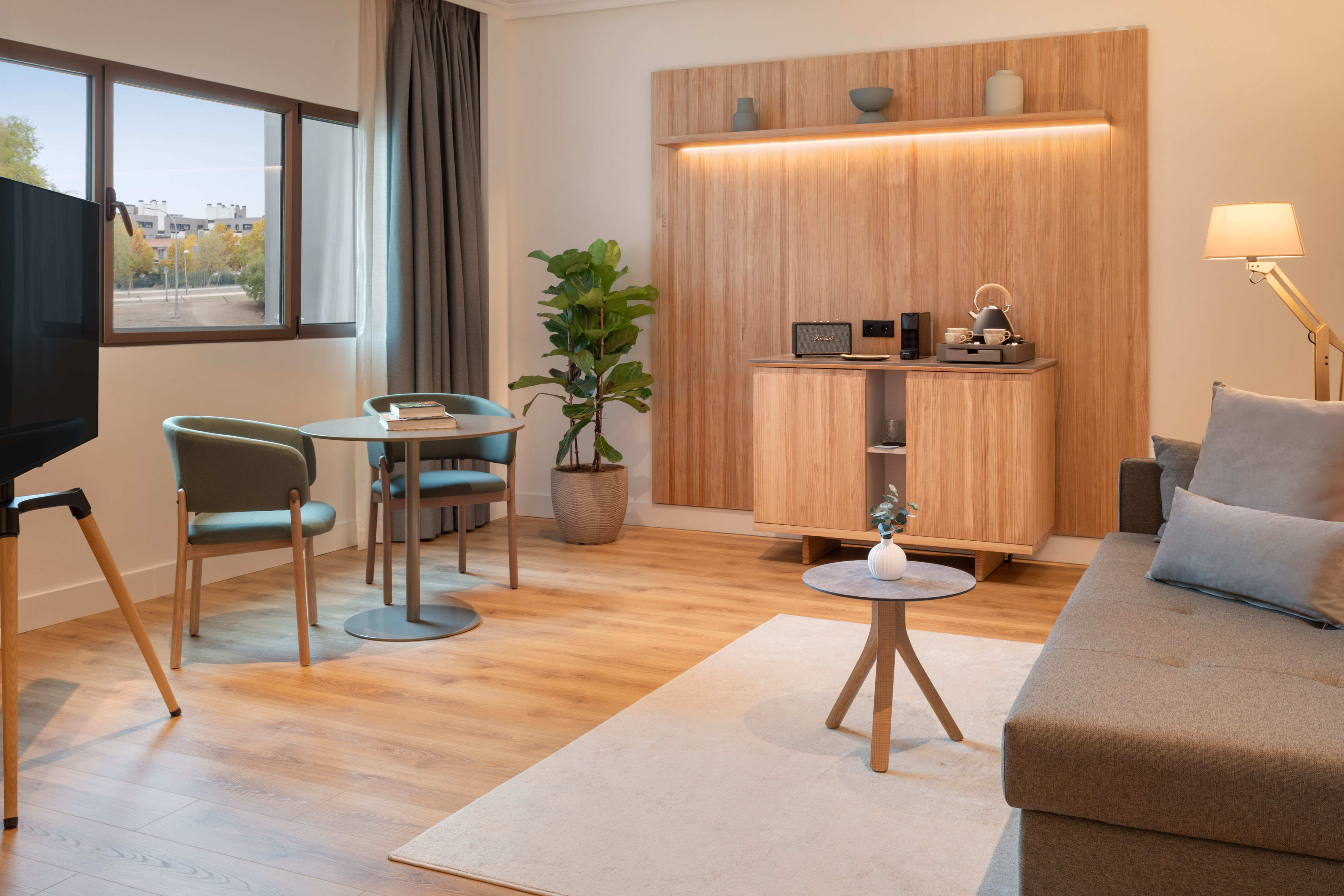 Modern apartment living area with wood furniture, sofa, dining table, window.