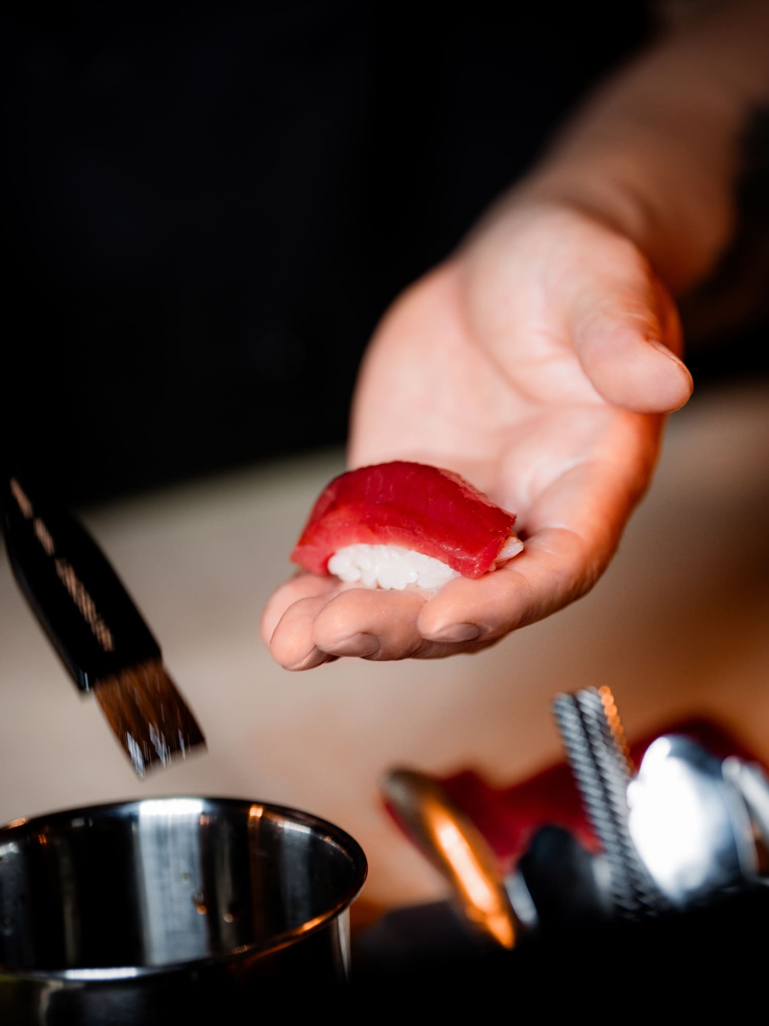 a hand holding a piece of sushi