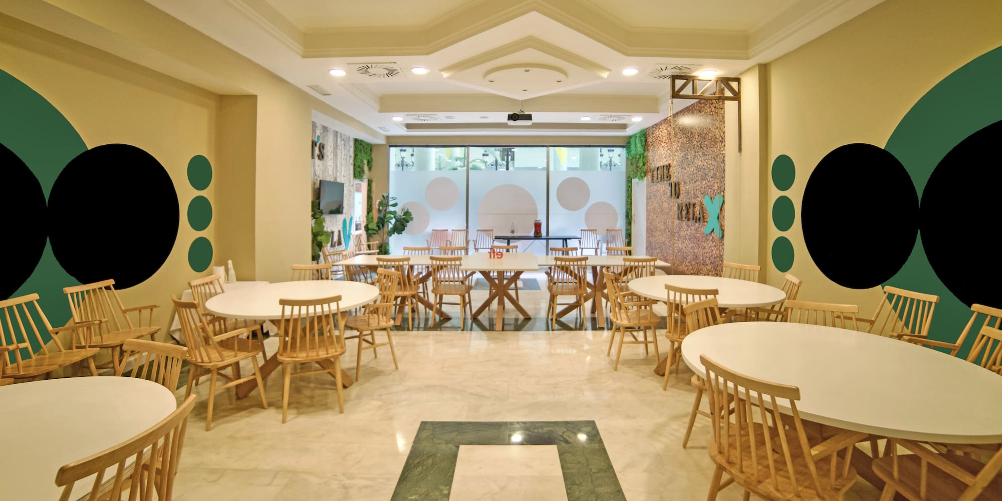 Modern restaurant dining area with white tables, wooden chairs, green accents.