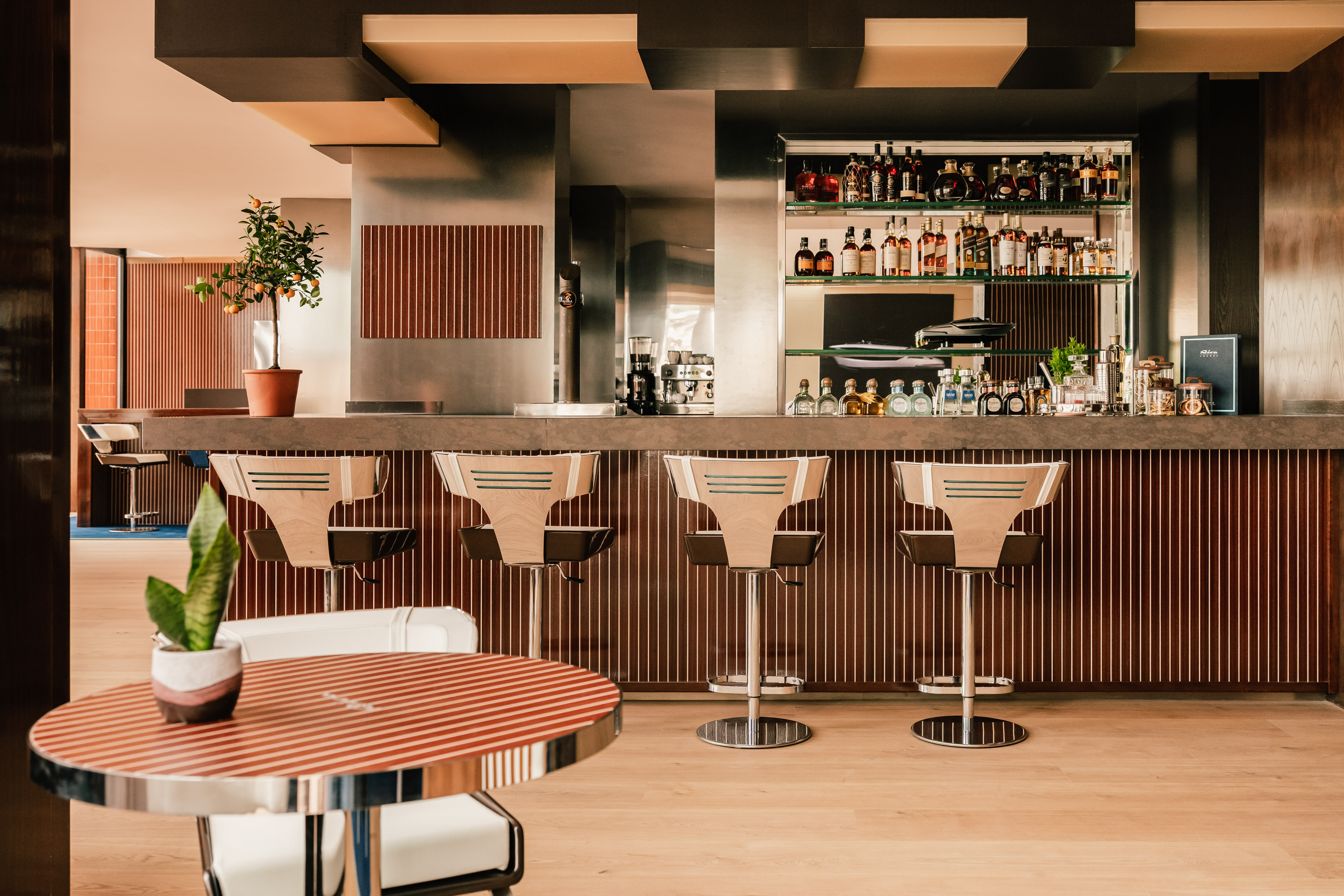 Modern bar with liquor bottles, sleek bar stools, and contemporary design.