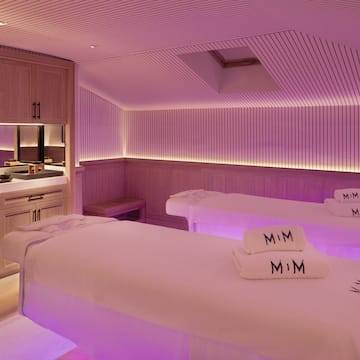 a room with beds and purple lighting