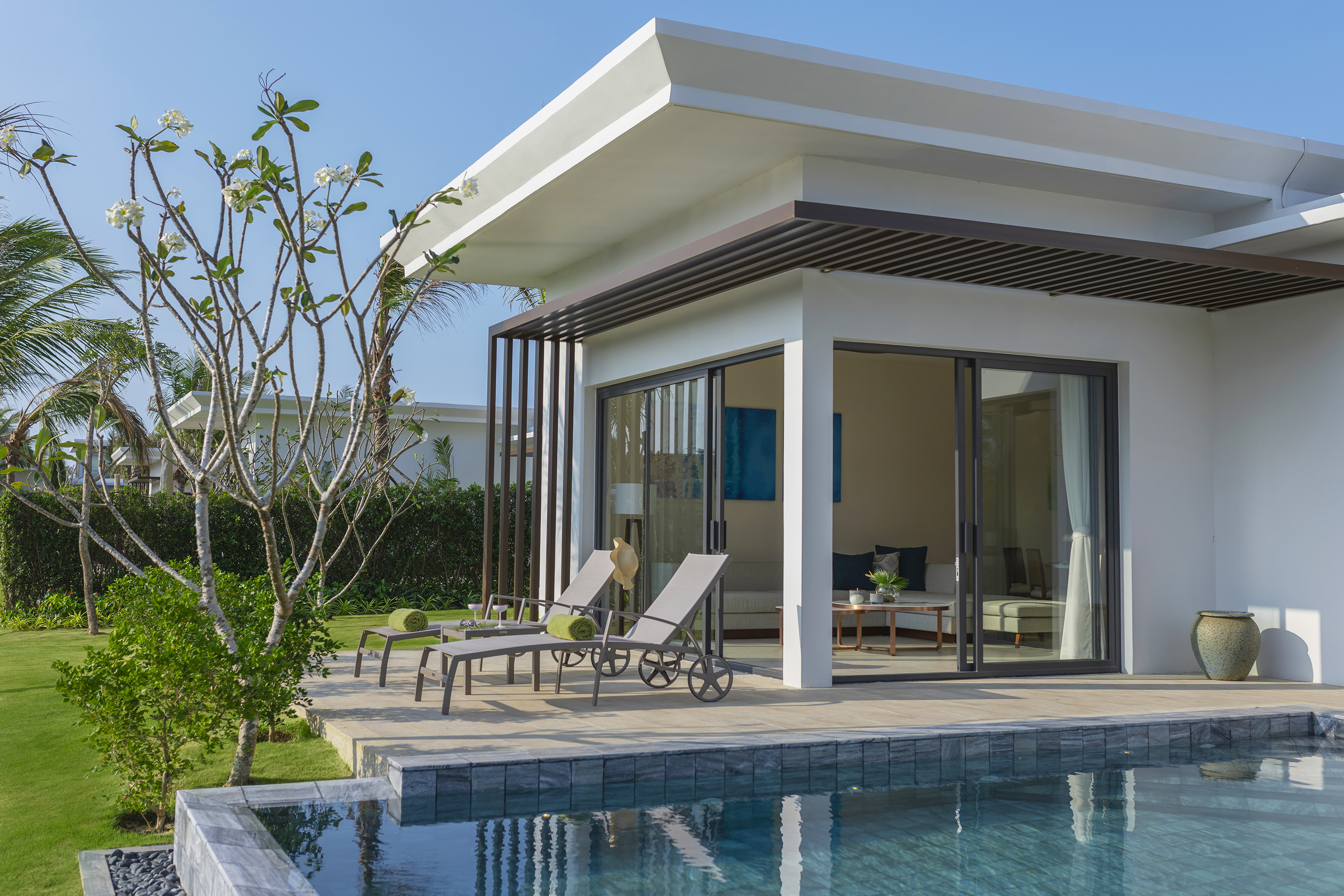 Luxury resort villa with private pool, patio, sun loungers, and tropical garden.