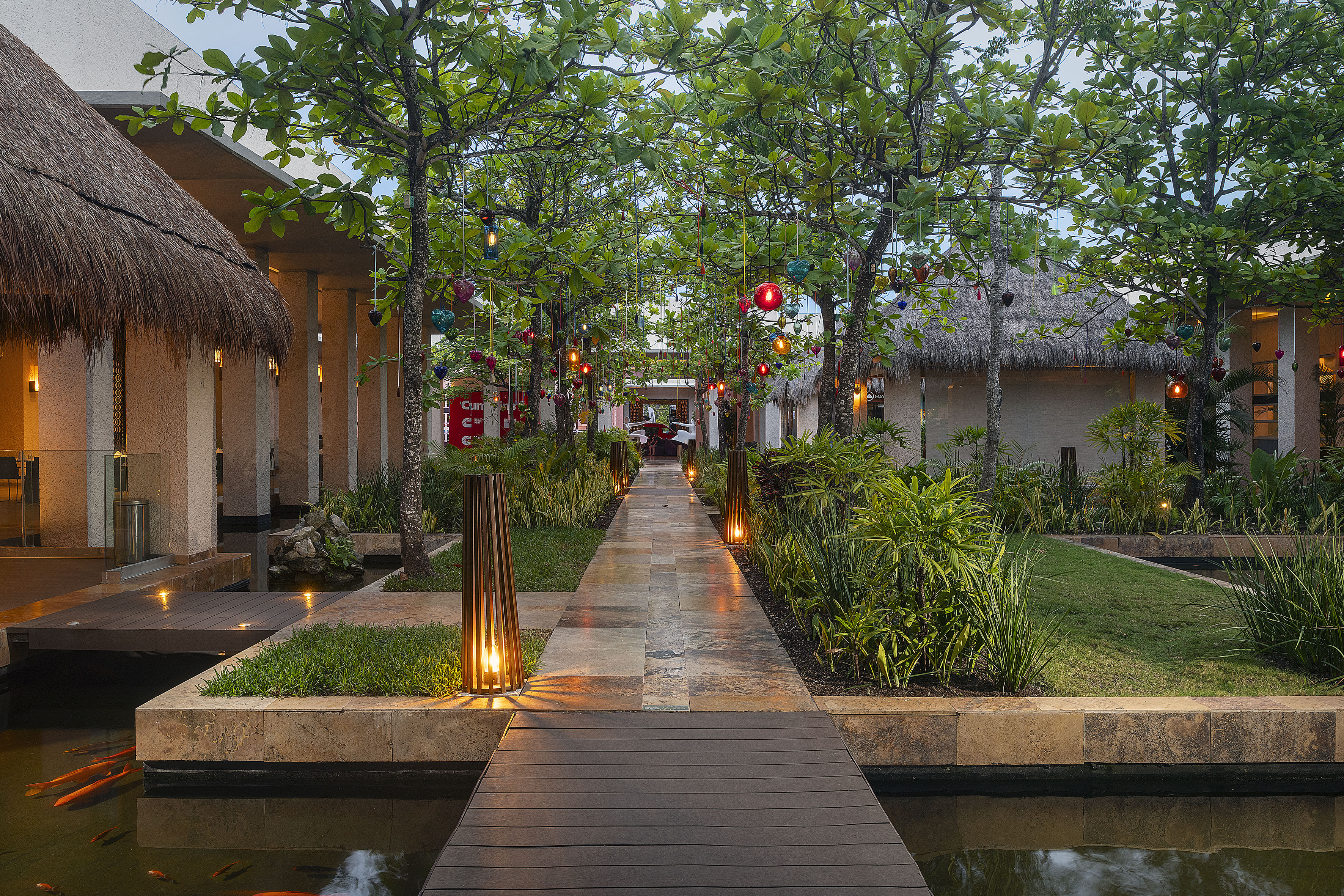 Tropical resort path, colorful hanging lights, lush gardens, and koi fish pond.