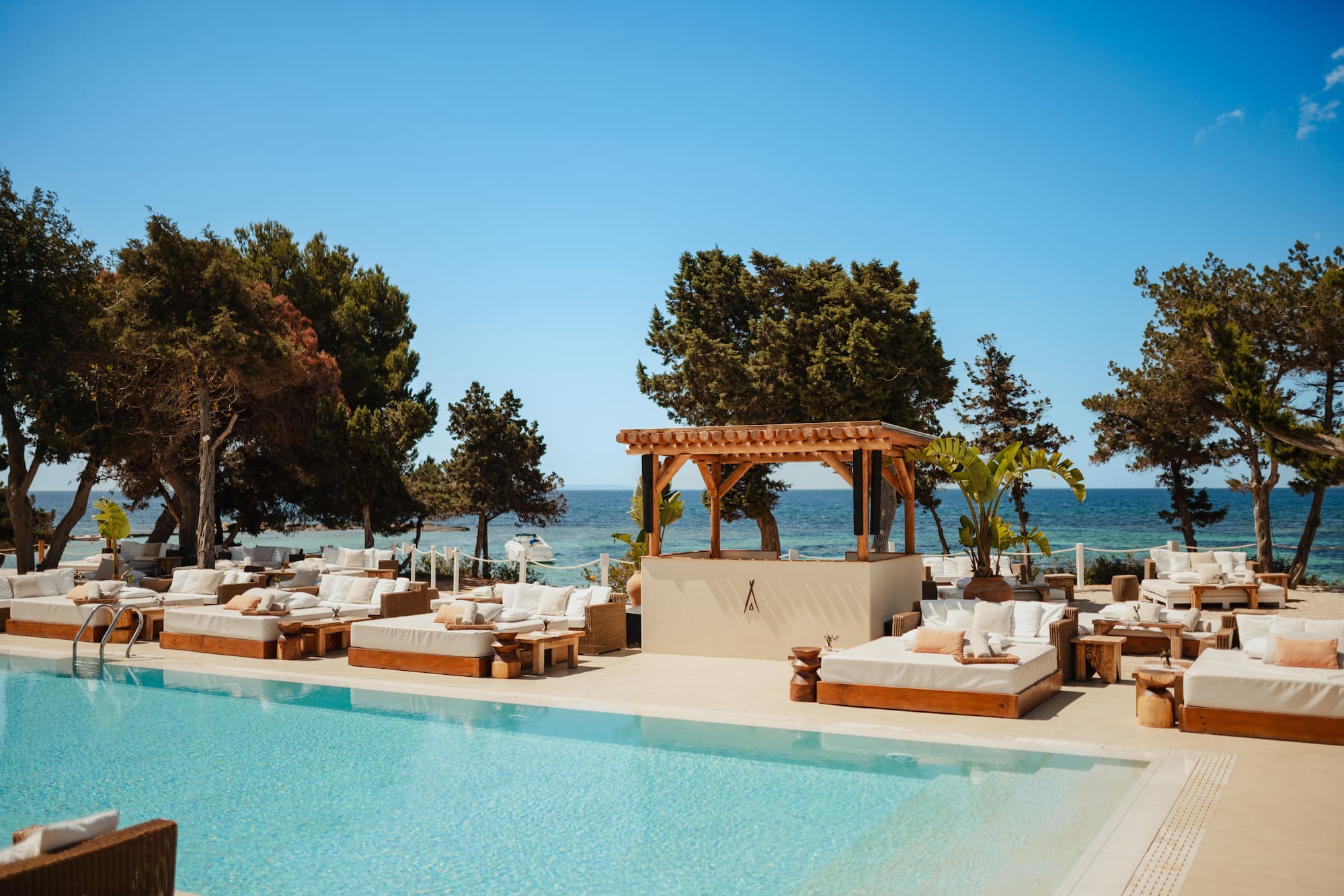 a pool with lounge chairs and trees and a blue sky