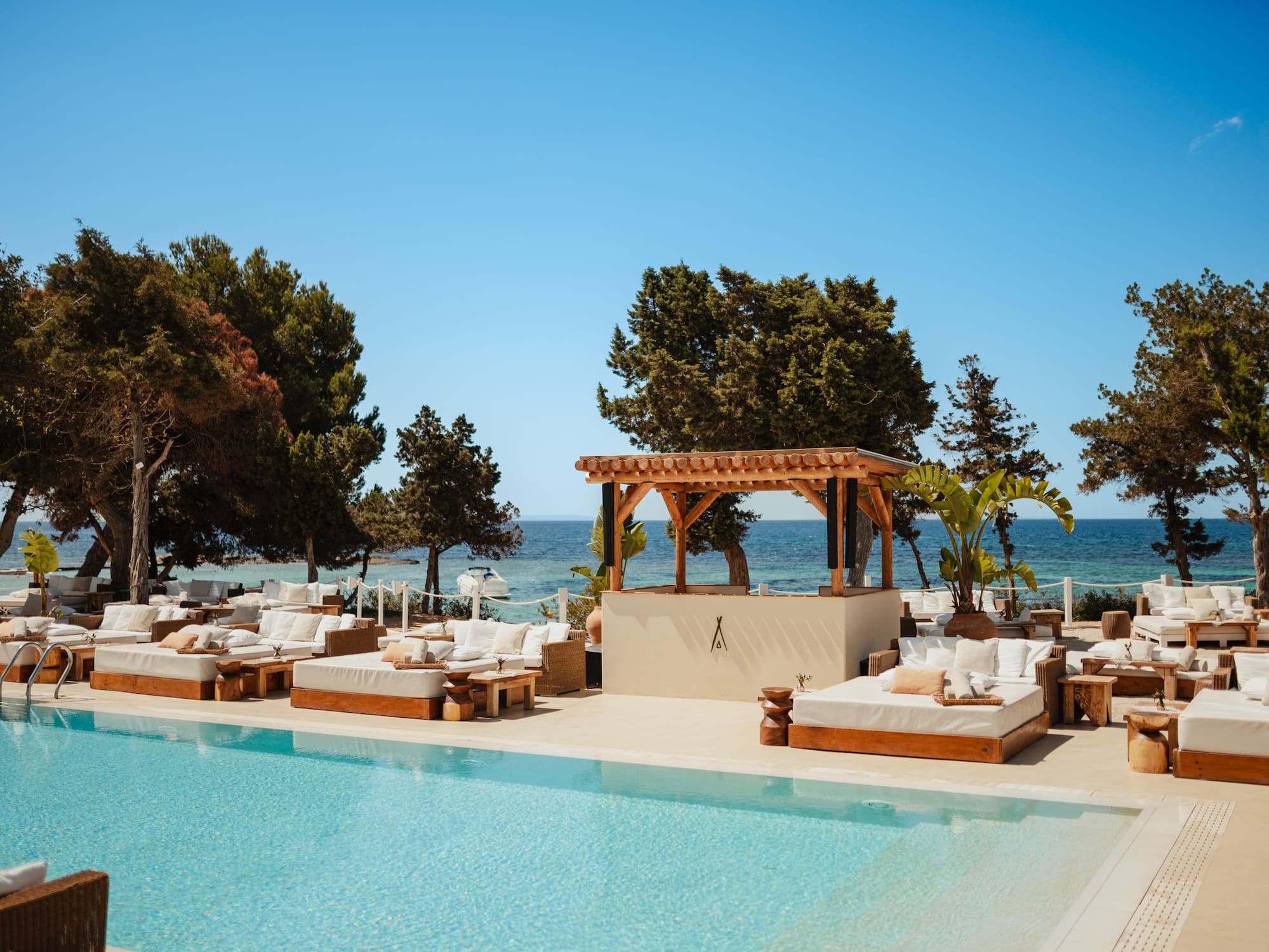 a pool with lounge chairs and trees and a blue sky