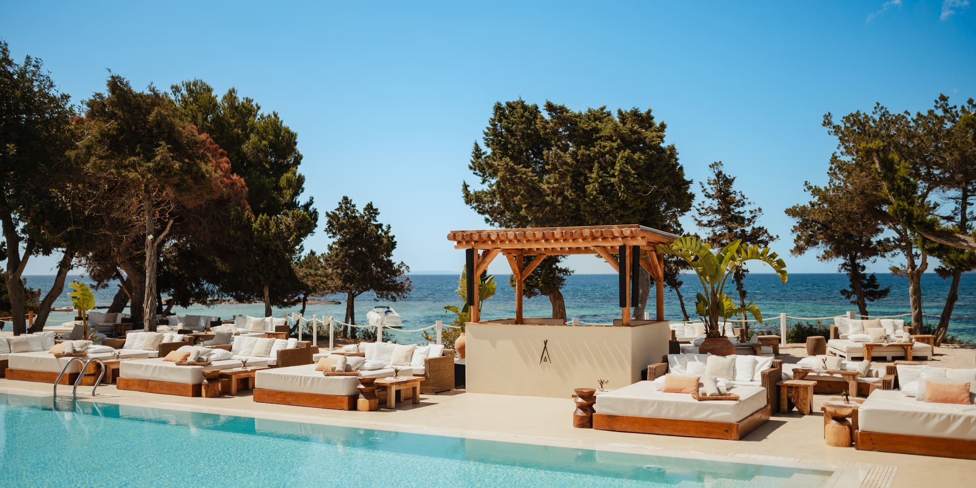 a pool with lounge chairs and trees and a blue sky