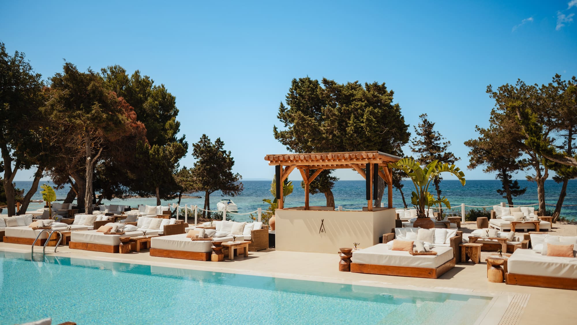 a pool with lounge chairs and trees and a blue sky