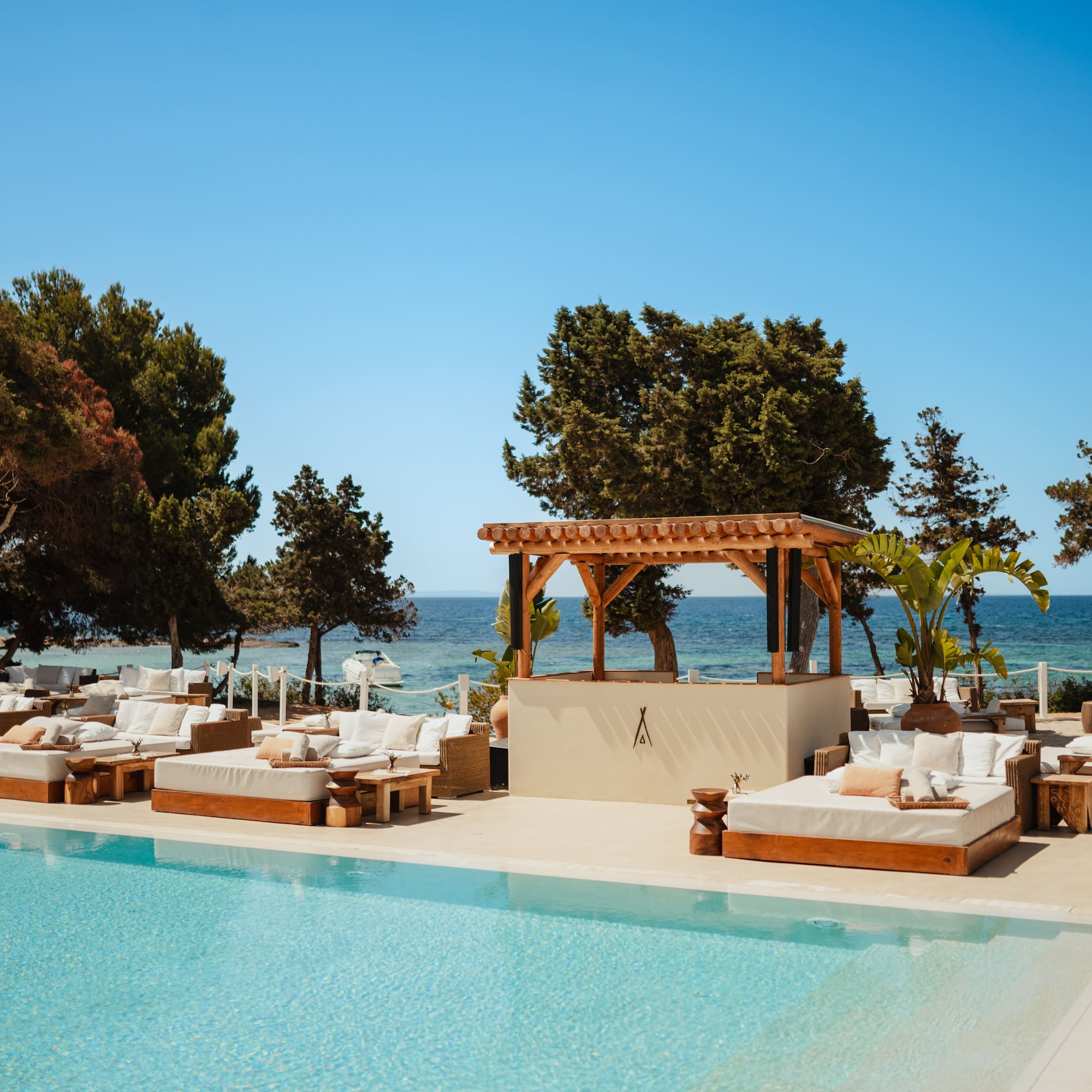a pool with lounge chairs and trees and a blue sky