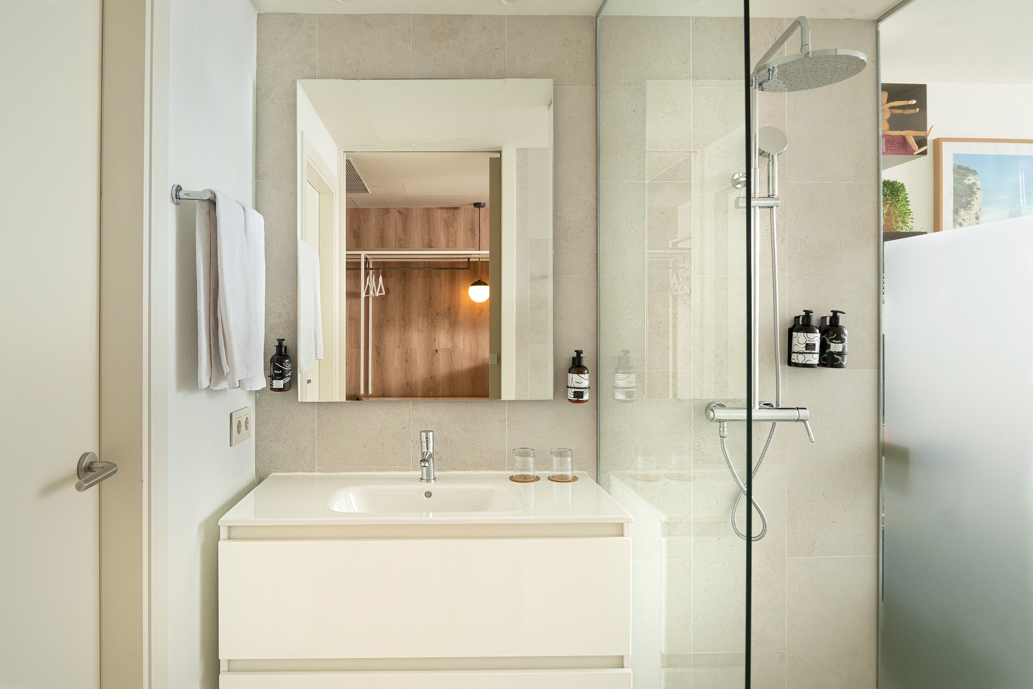 Sleek modern bathroom with white vanity, mirror, and glass shower.