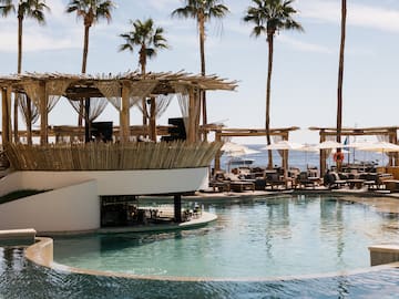 a pool with a bar and chairs and a deck with a large deck and palm trees